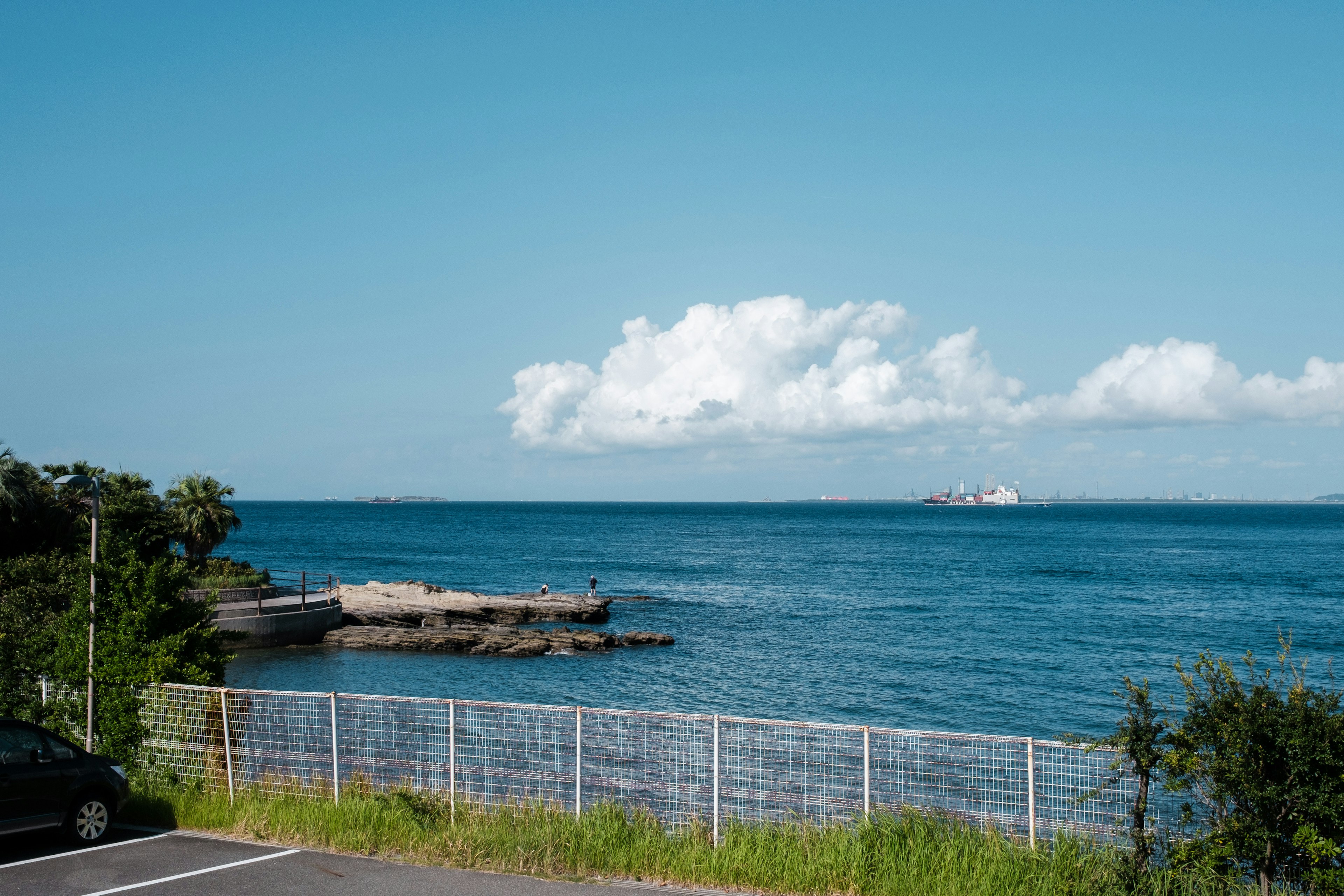 Scenic view of blue ocean and white clouds with a breakwater