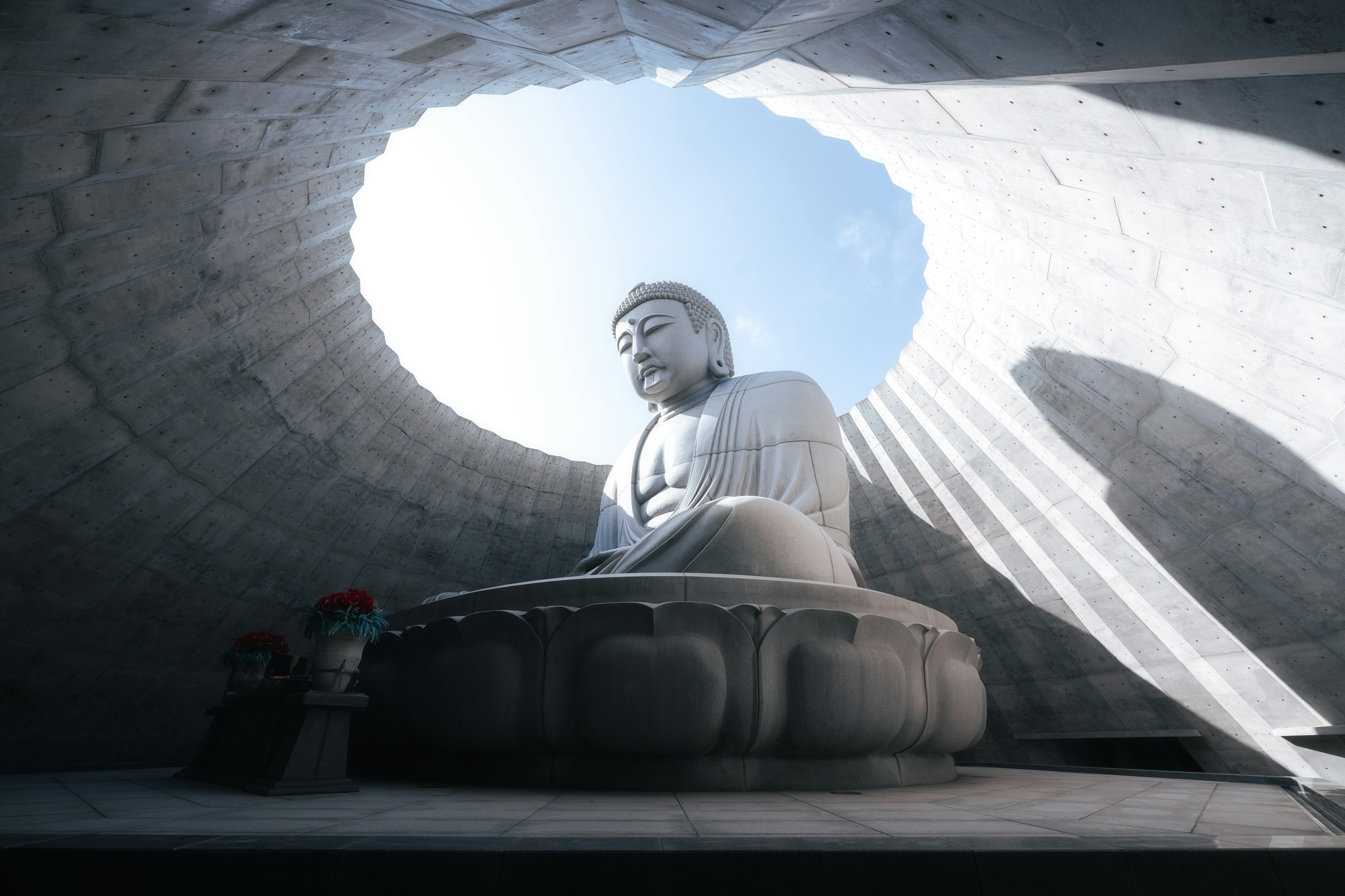 Patung Buddha besar di ruang modern dengan cahaya yang masuk dari atas