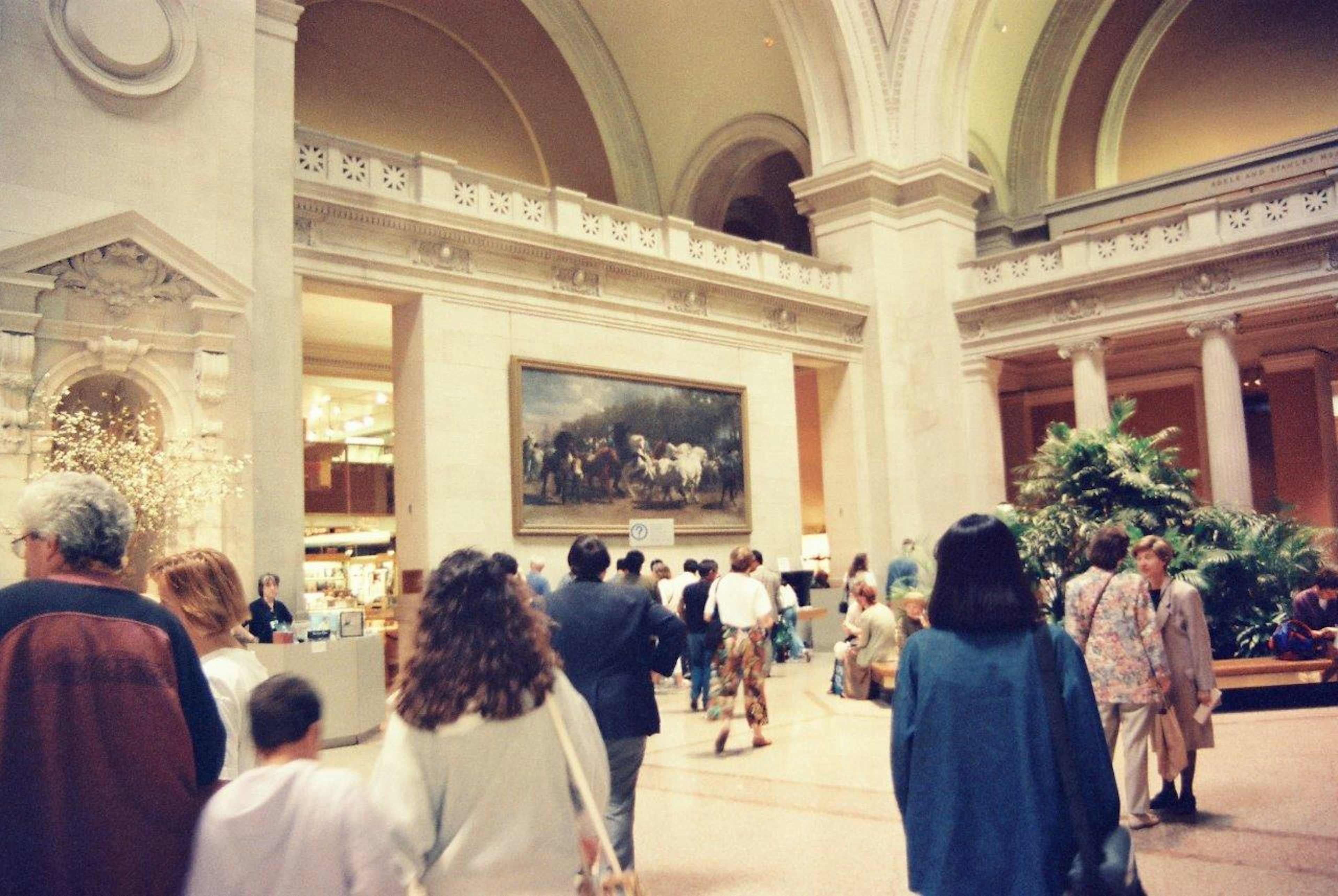 People walking inside an art museum with a large painting on display