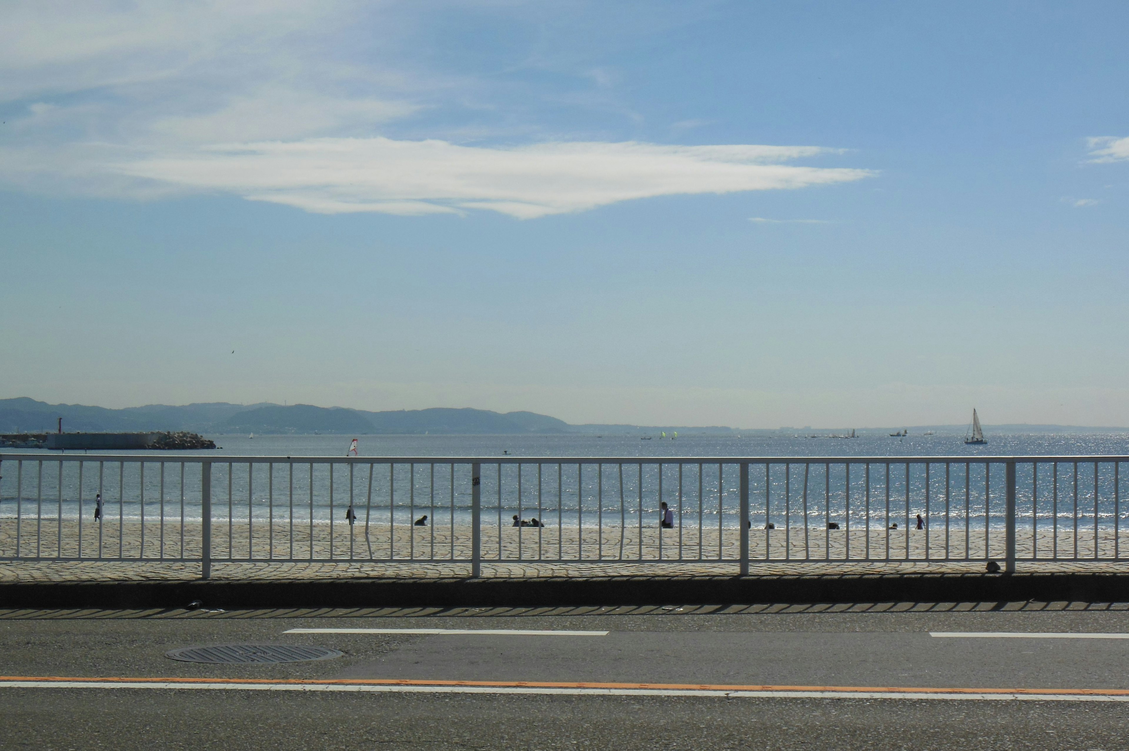 A road with a fence alongside a blue sea and sky landscape