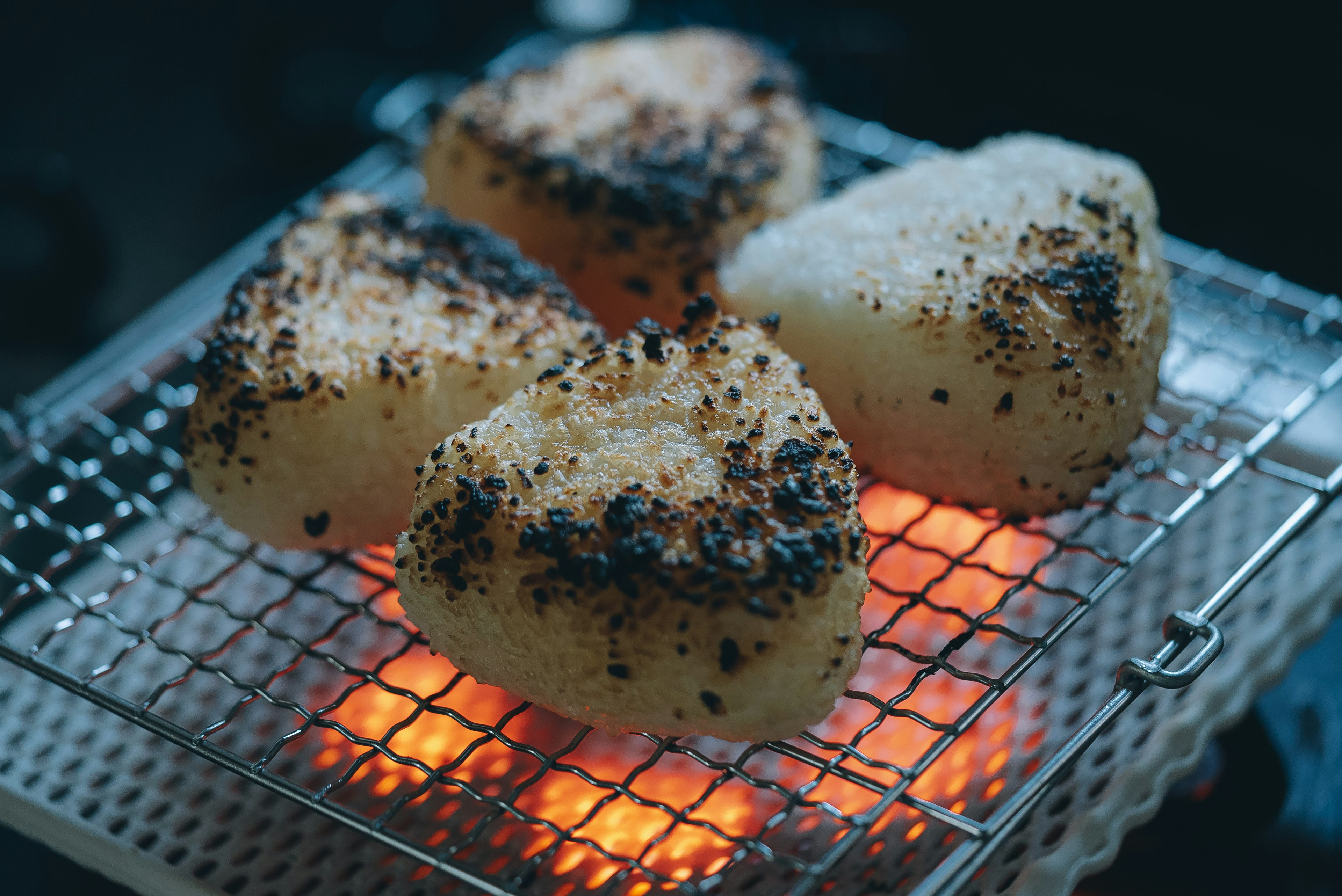 Grilled rice balls on a wire rack over glowing embers