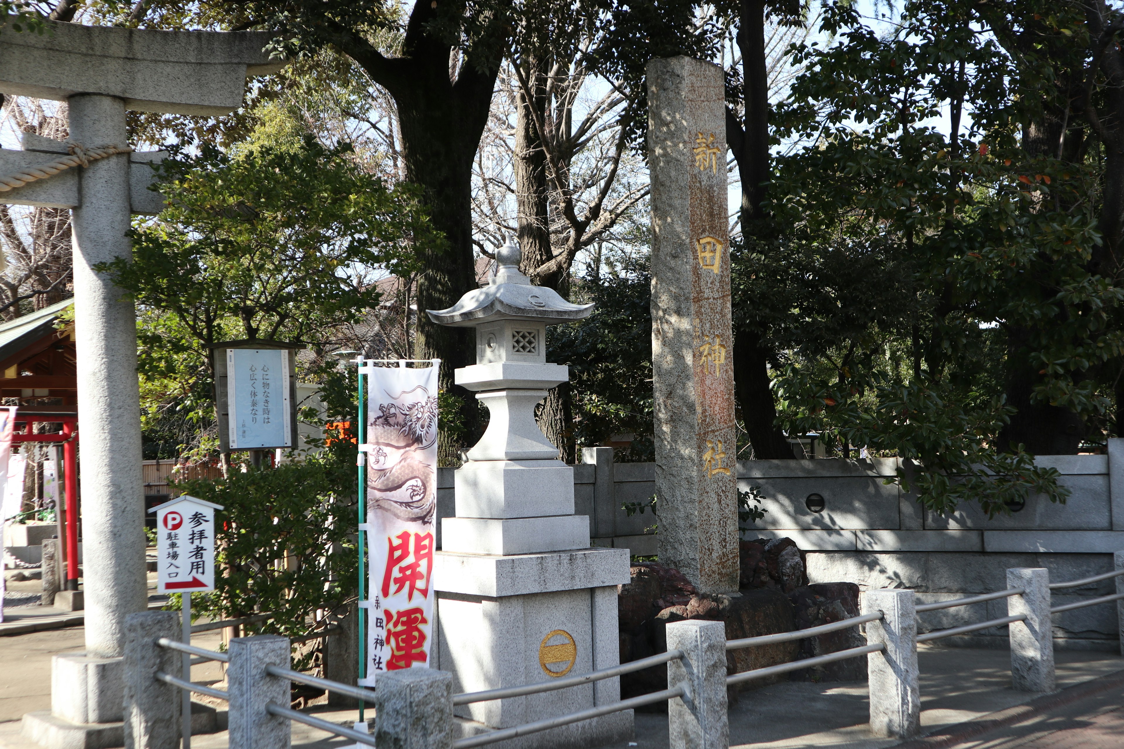 古老神社入口處的白色燈籠和石碑被綠色樹木環繞，環境寧靜