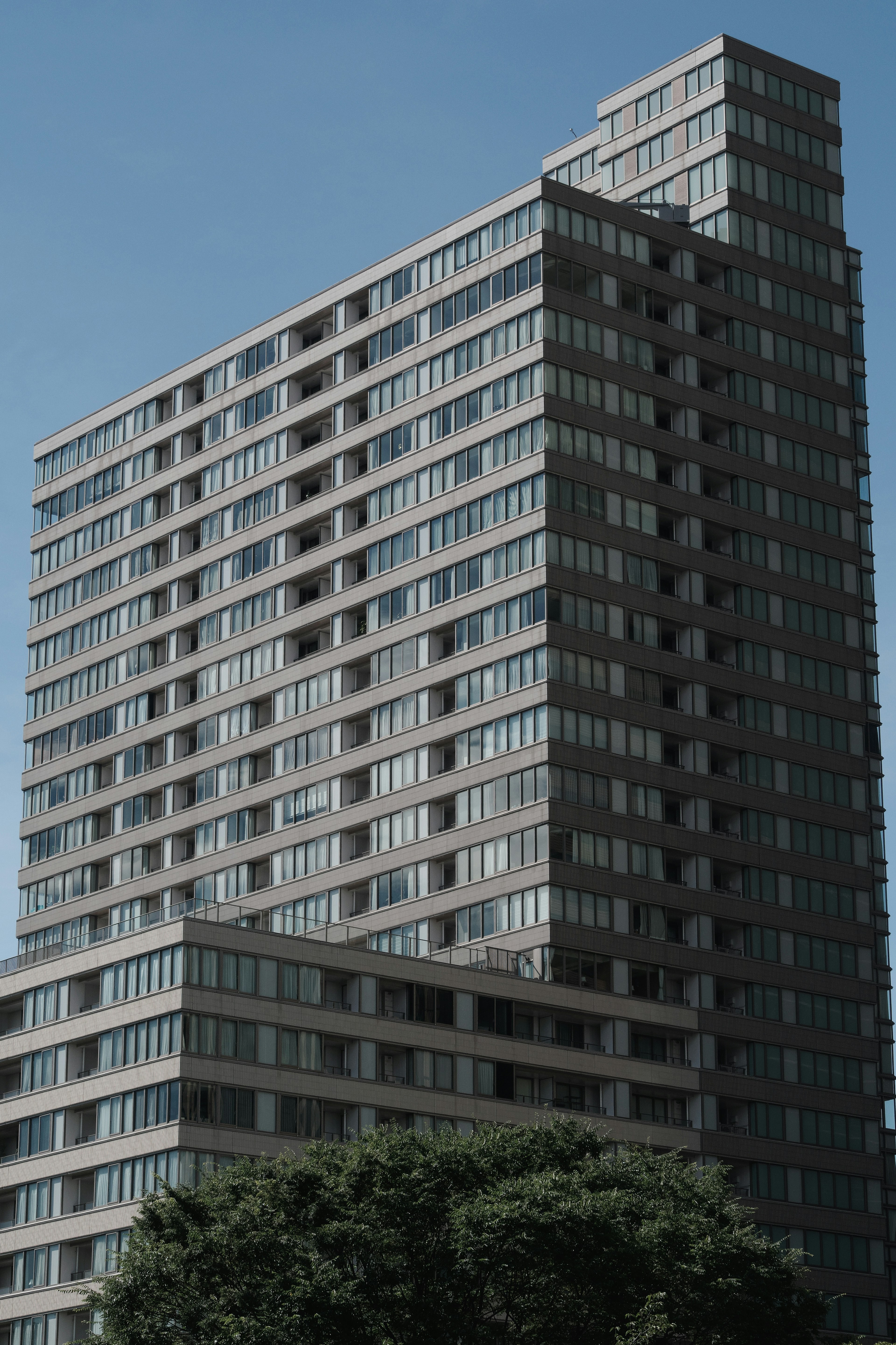 Modern high-rise building with glass windows surrounded by greenery