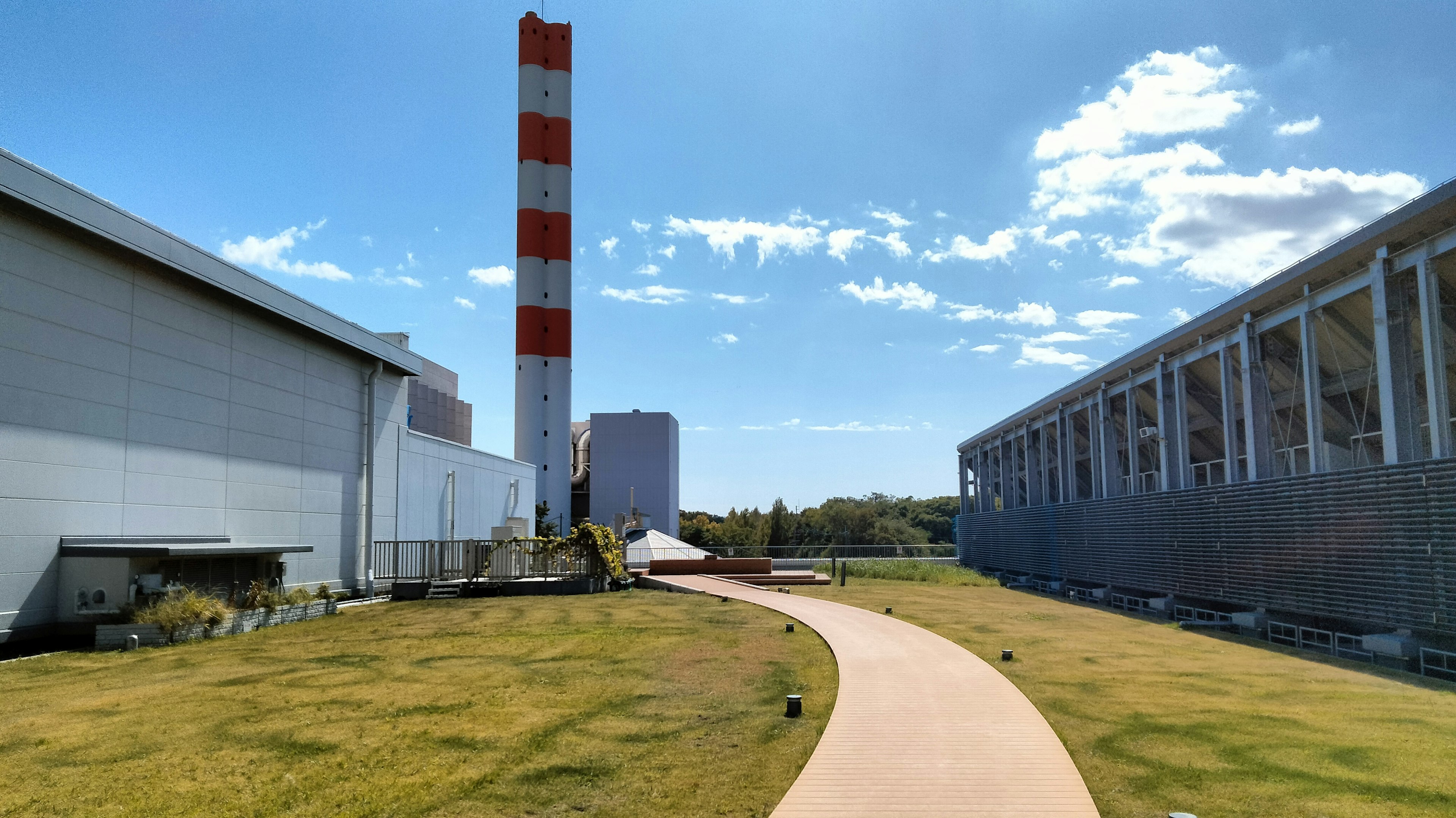 Paysage industriel spacieux avec une grande cheminée et des bâtiments sous un ciel bleu