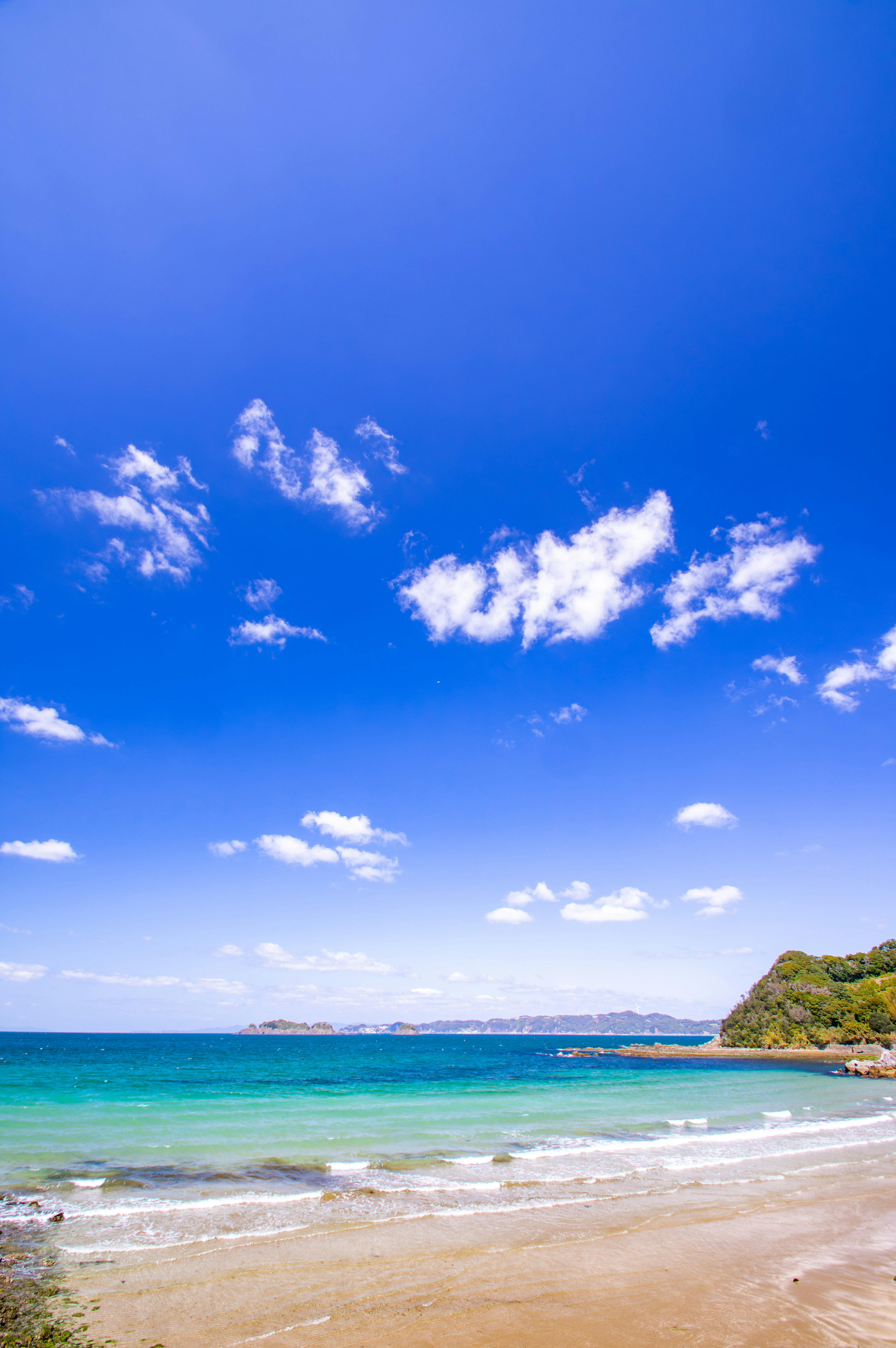 Una scena di spiaggia con cielo blu e nuvole bianche acqua turchese e spiaggia di sabbia