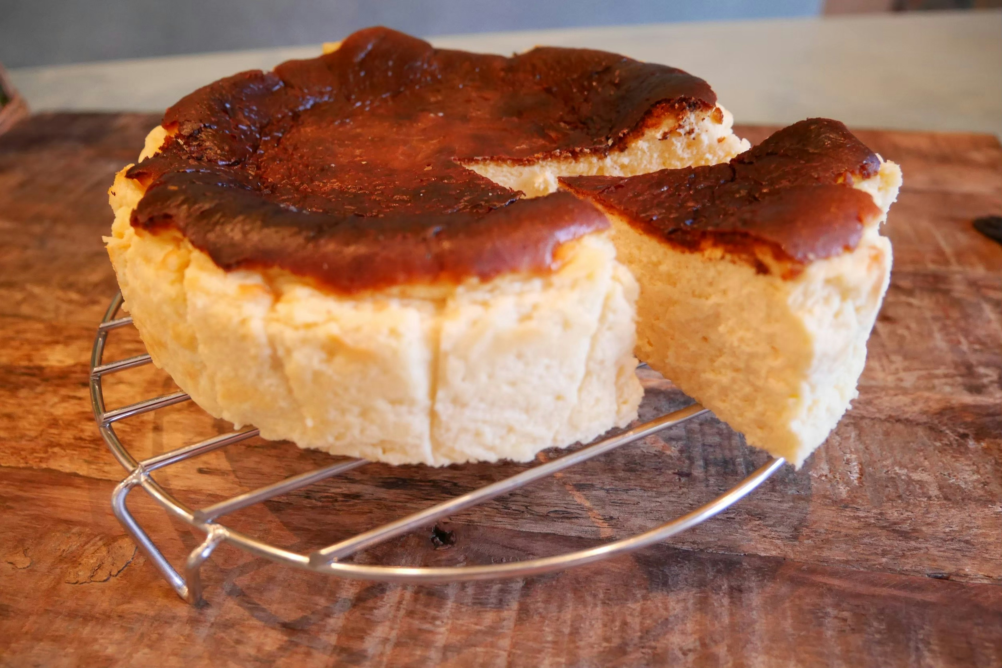 Browned cheesecake on a wire rack with a slice cut out