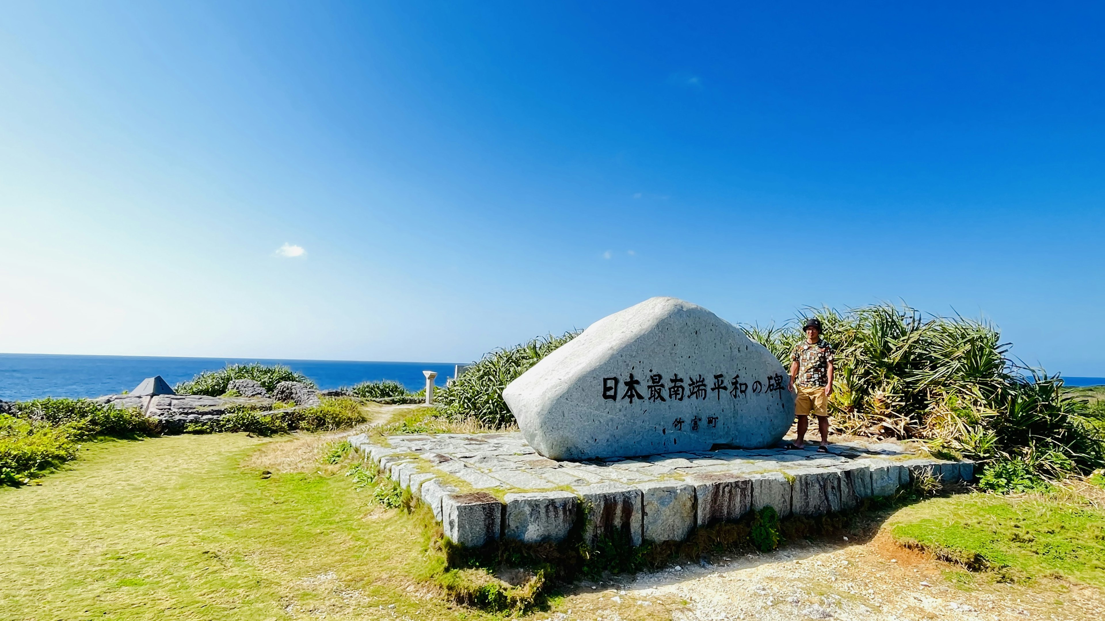 刻有铭文的石碑，周围是绿色草地和蓝色海洋