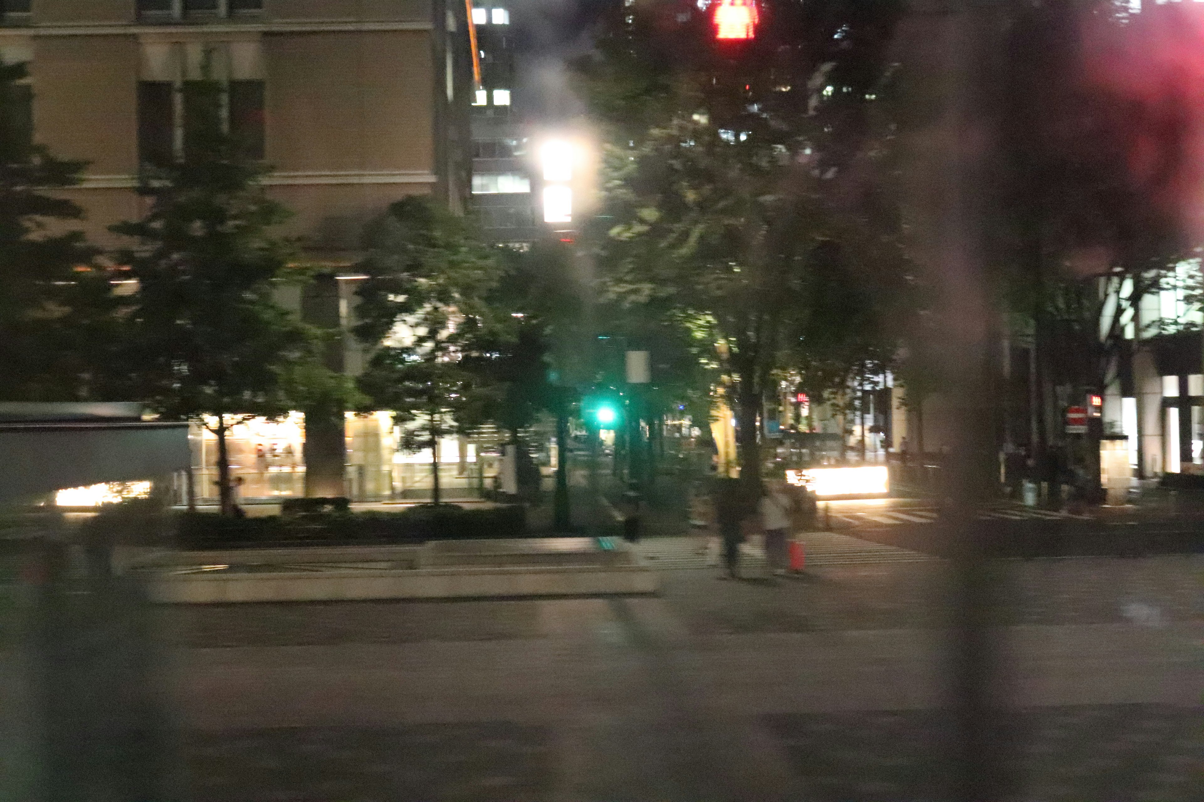 Nächtliche Stadtansicht mit grünem Ampelsignal und Fußgängern