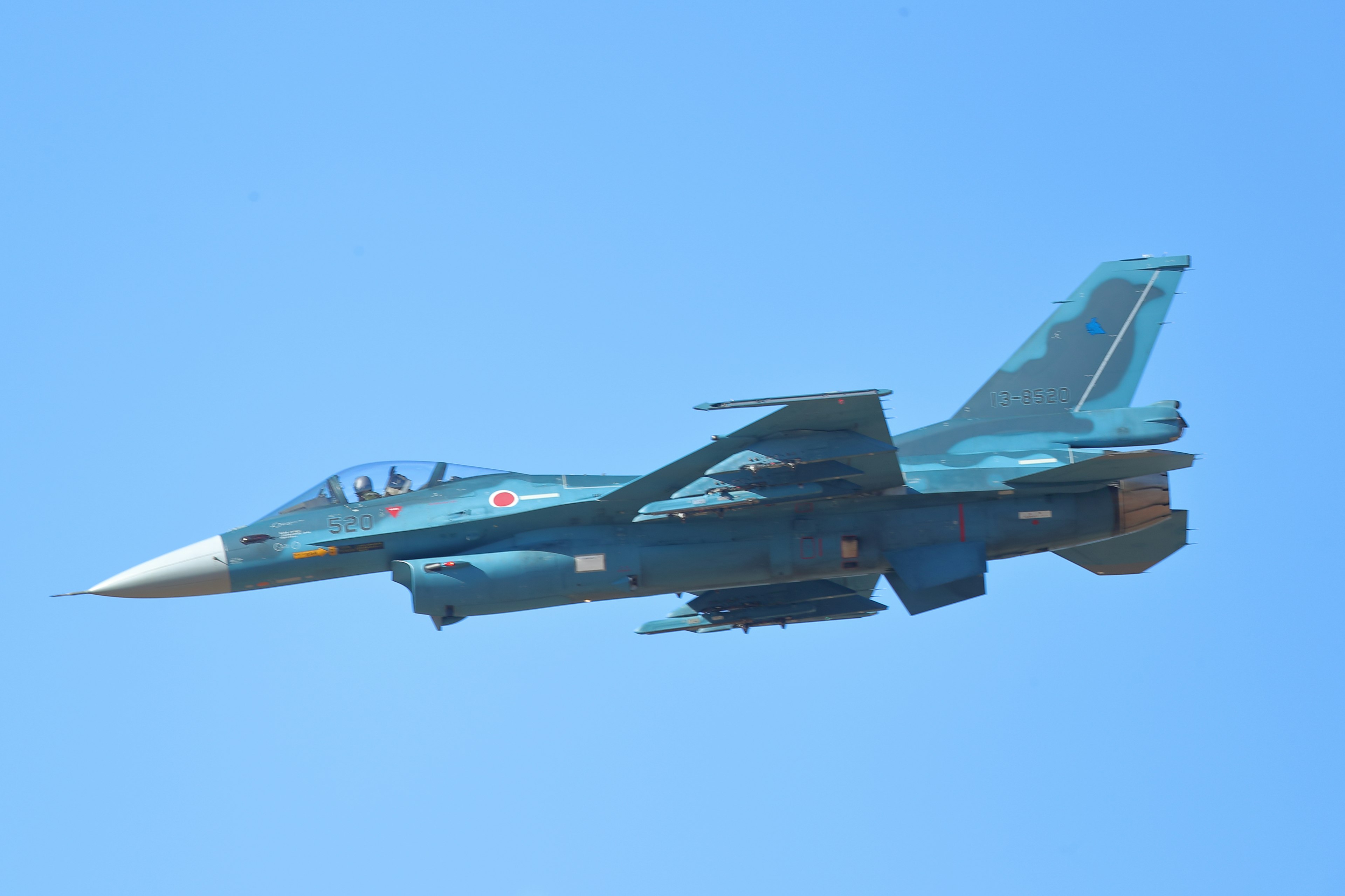 Side view of a fighter jet flying against a blue sky