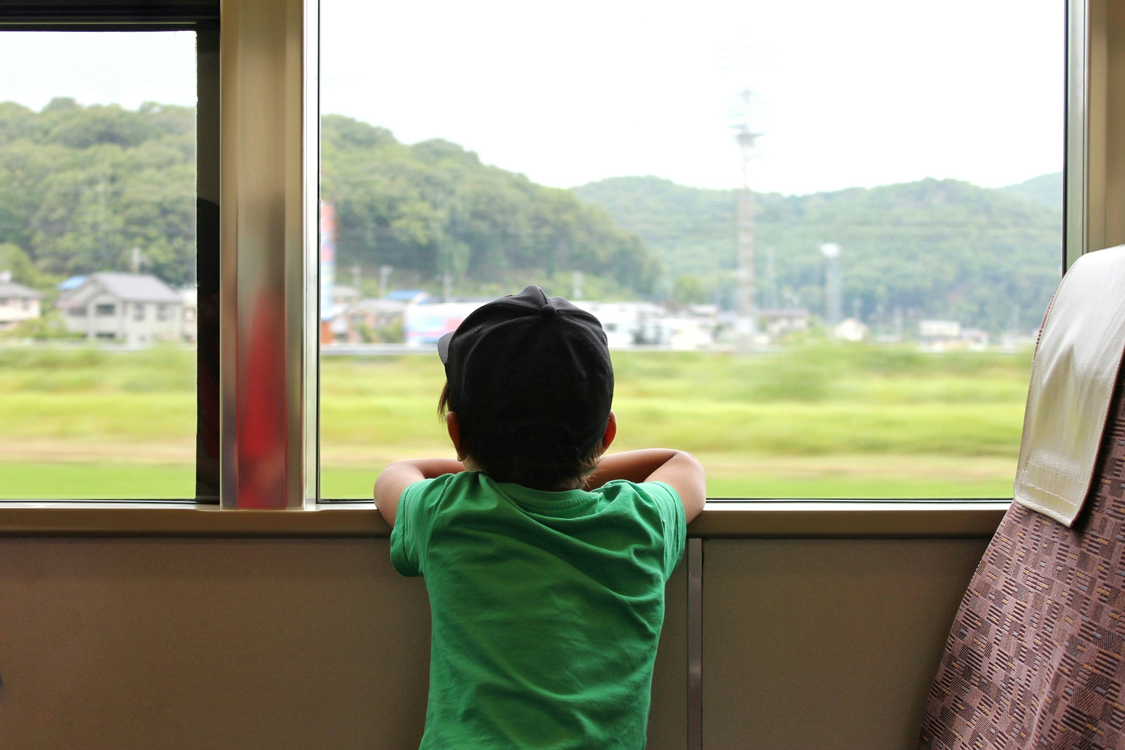 Un enfant en chemise verte regardant par la fenêtre d'un train