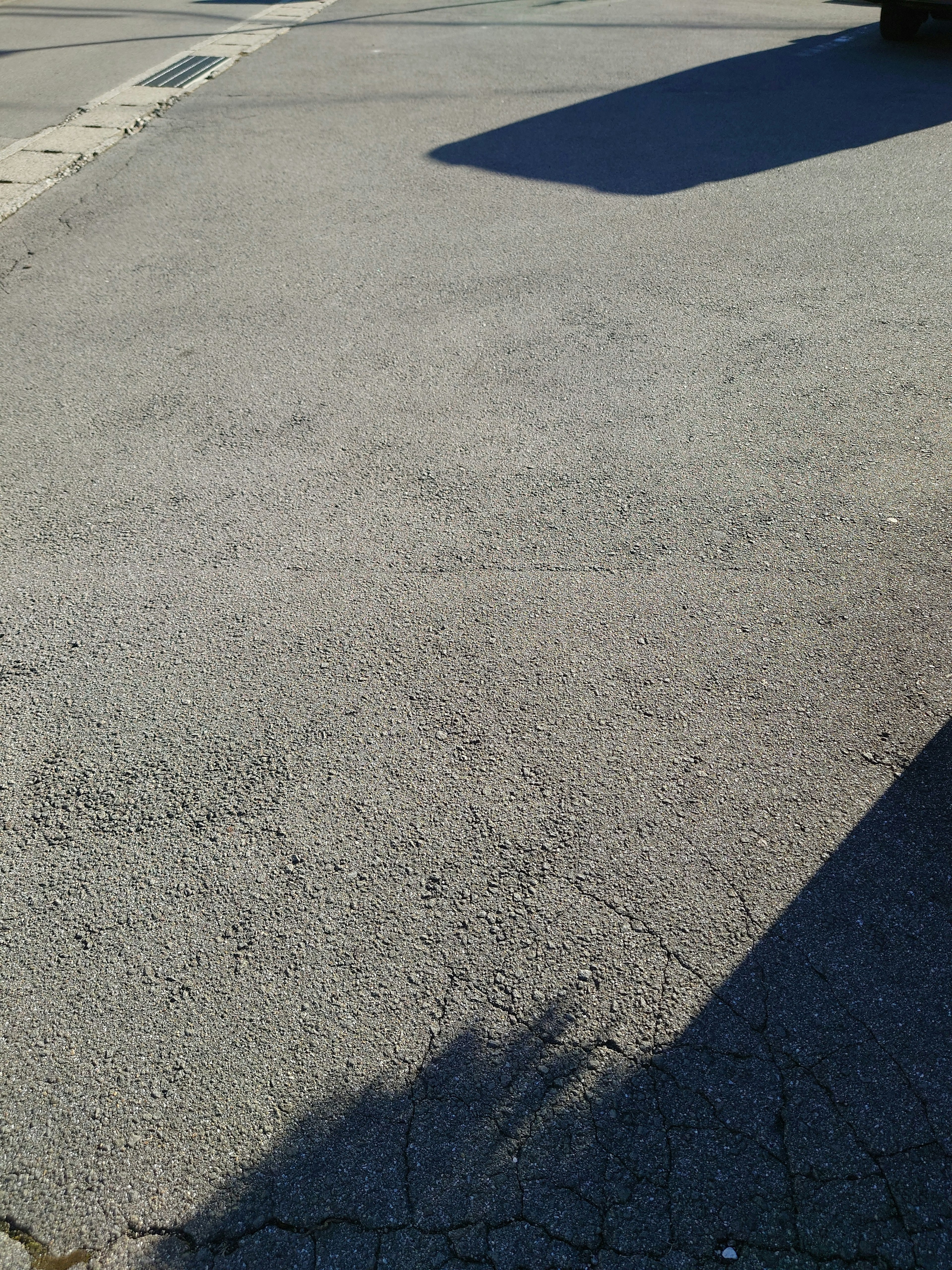 A simple image showing a portion of a paved road with visible shadows