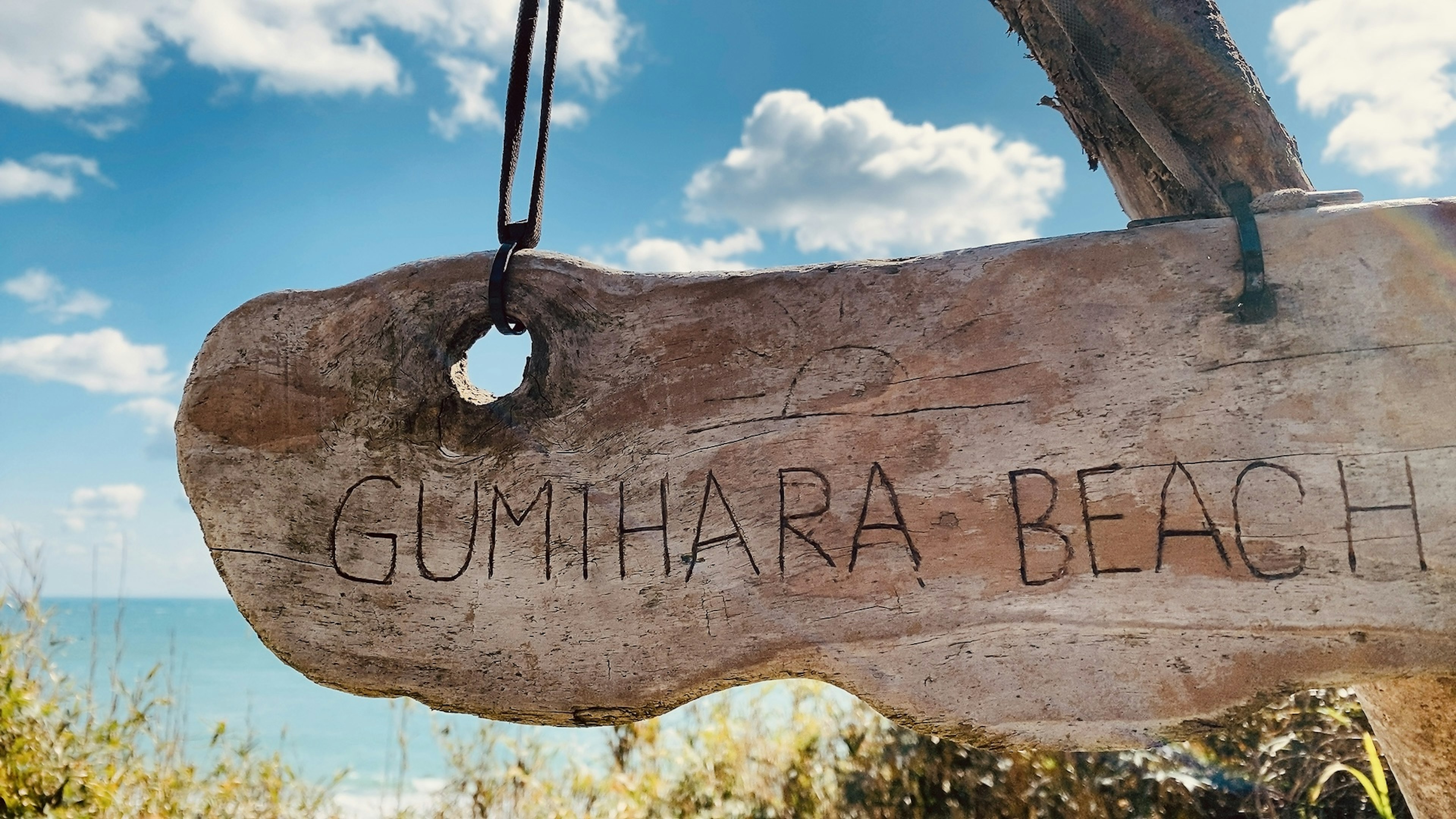 Holzschild für Gunthara Beach mit blauem Himmel und Ozean im Hintergrund