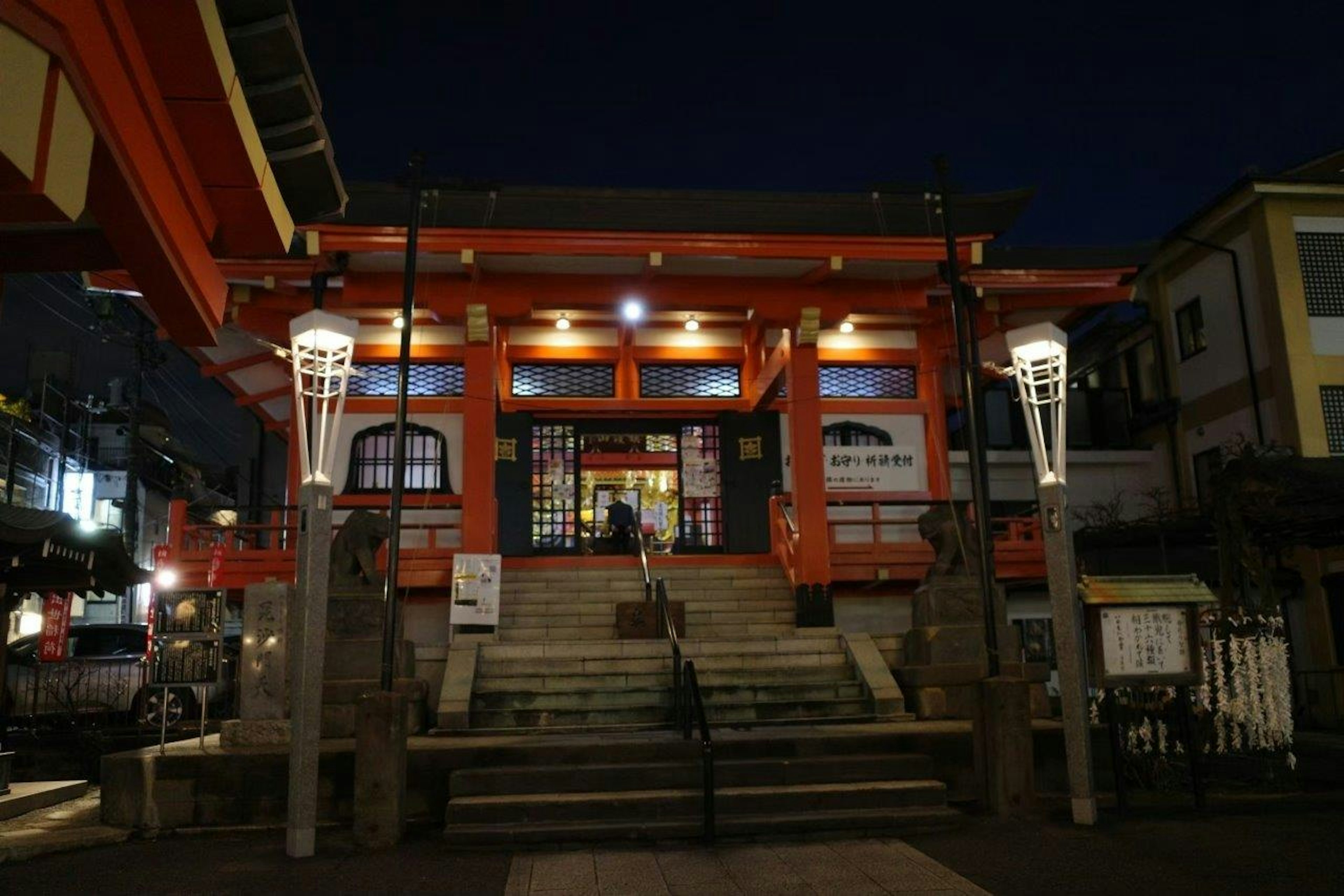 Beleuchteter Eingang eines roten Schreins mit Treppe bei Nacht