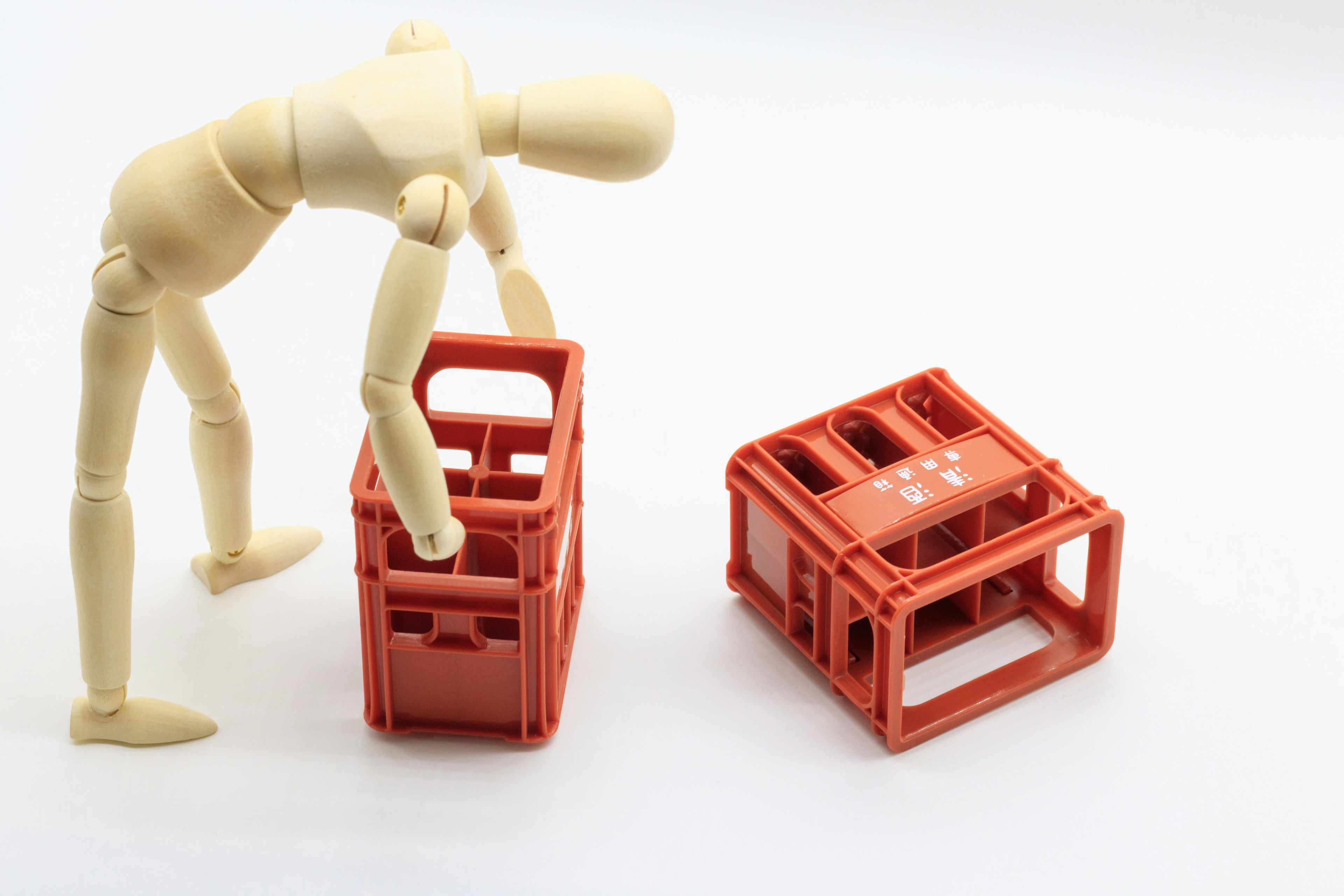 Wooden mannequin lifting a red plastic crate