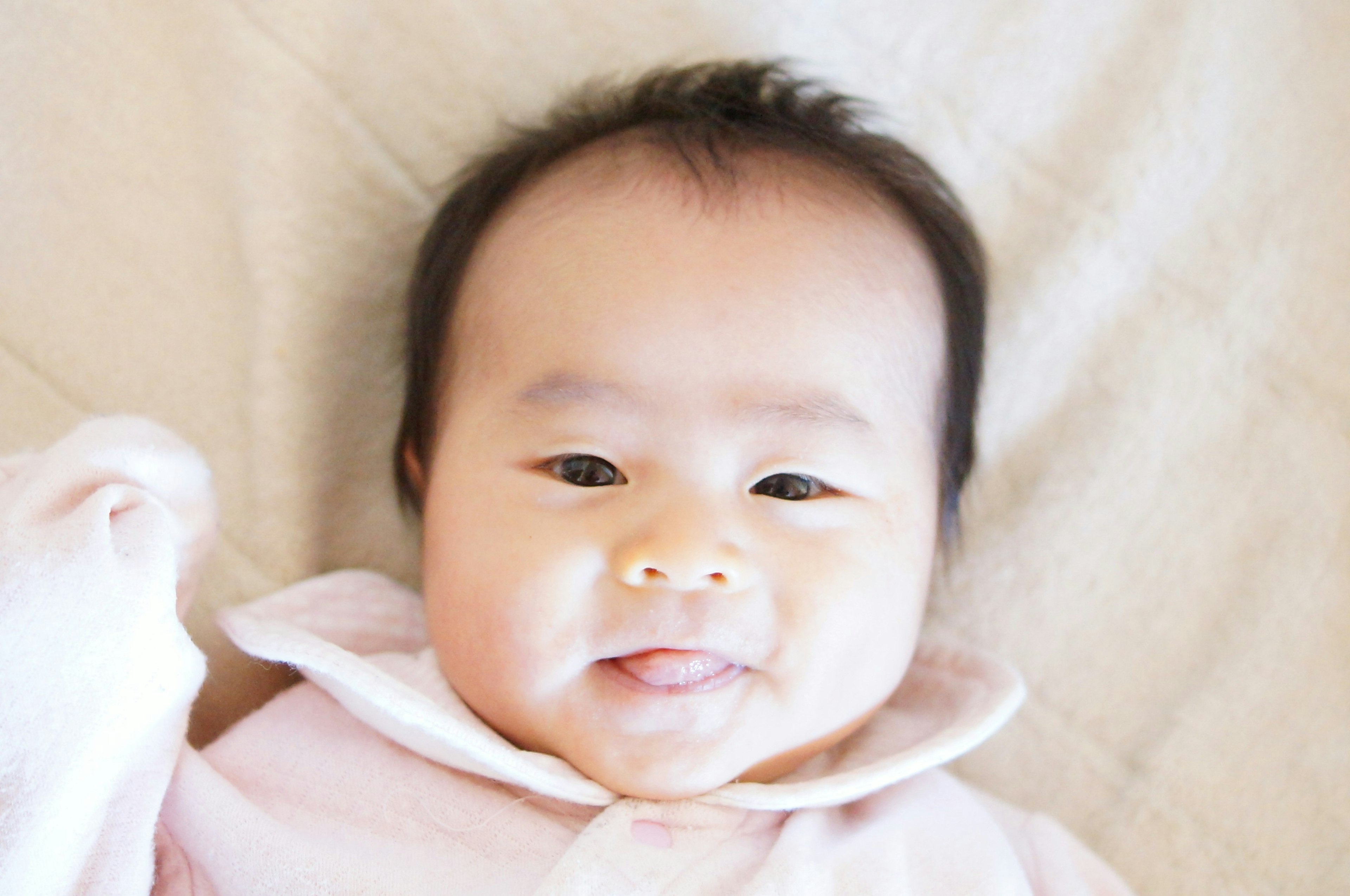 A smiling baby wearing a light pink outfit