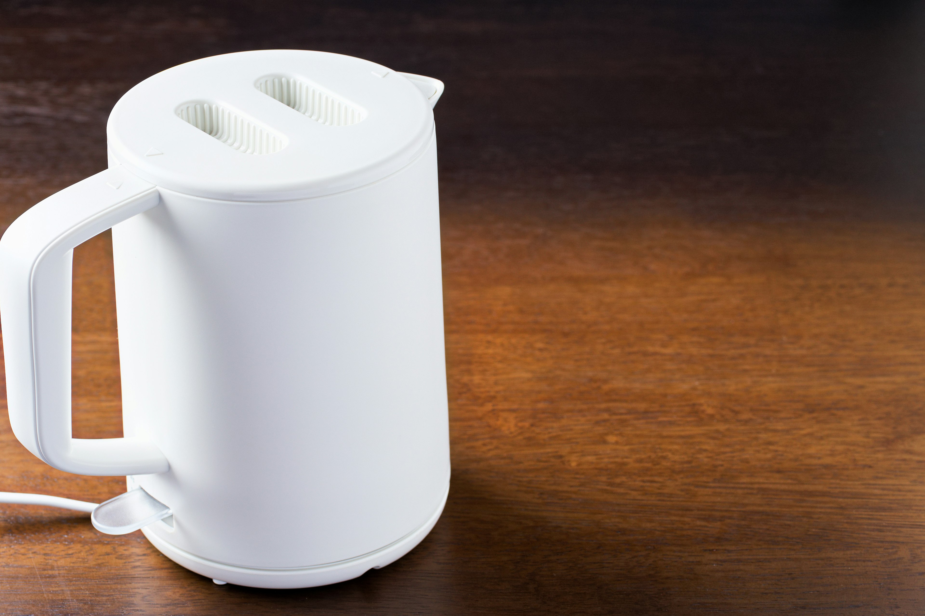 A white electric kettle placed on a wooden table