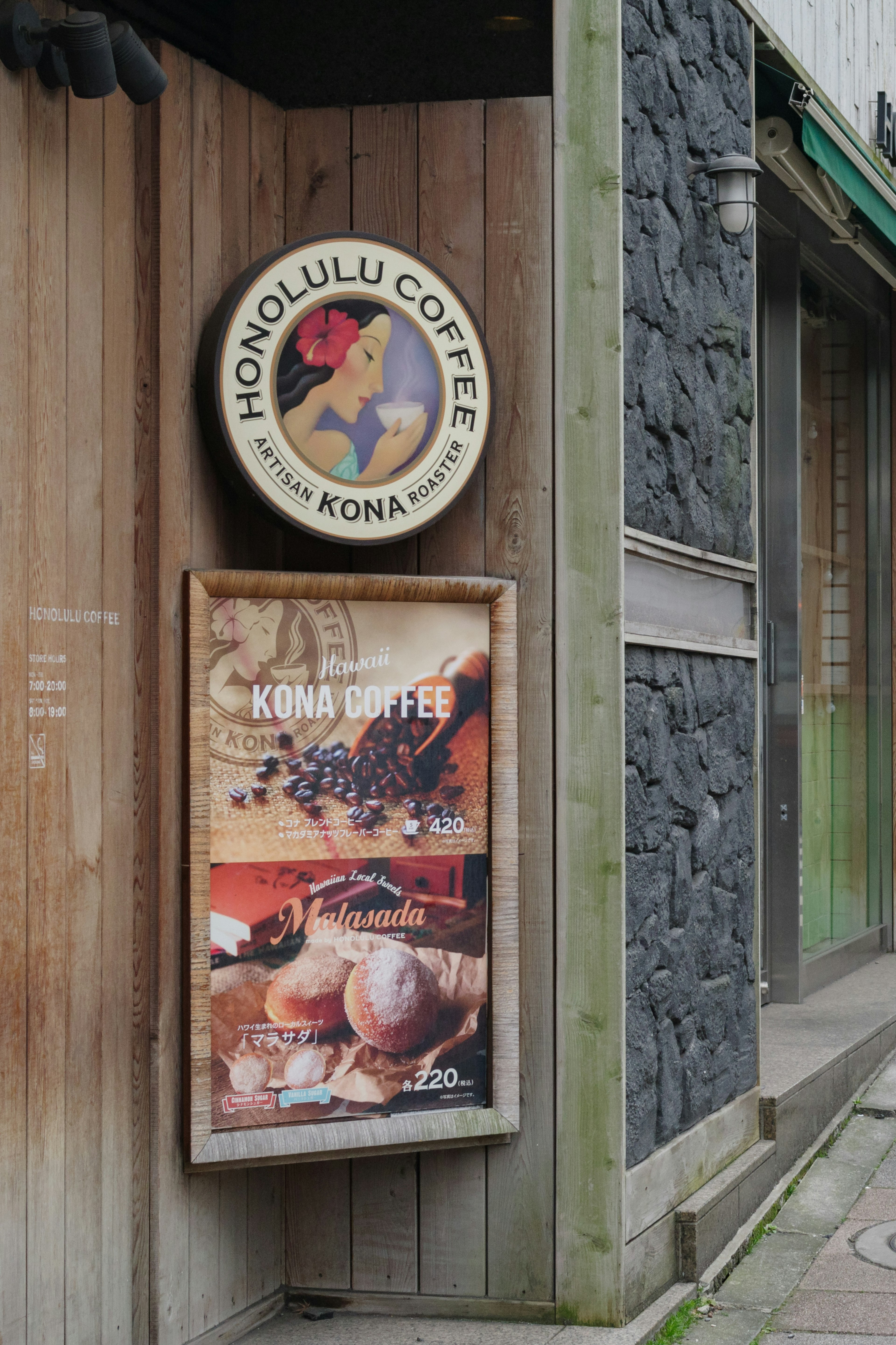 Exterior de una tienda con un letrero de Honolulu Coffee y un cartel de Kona Coffee