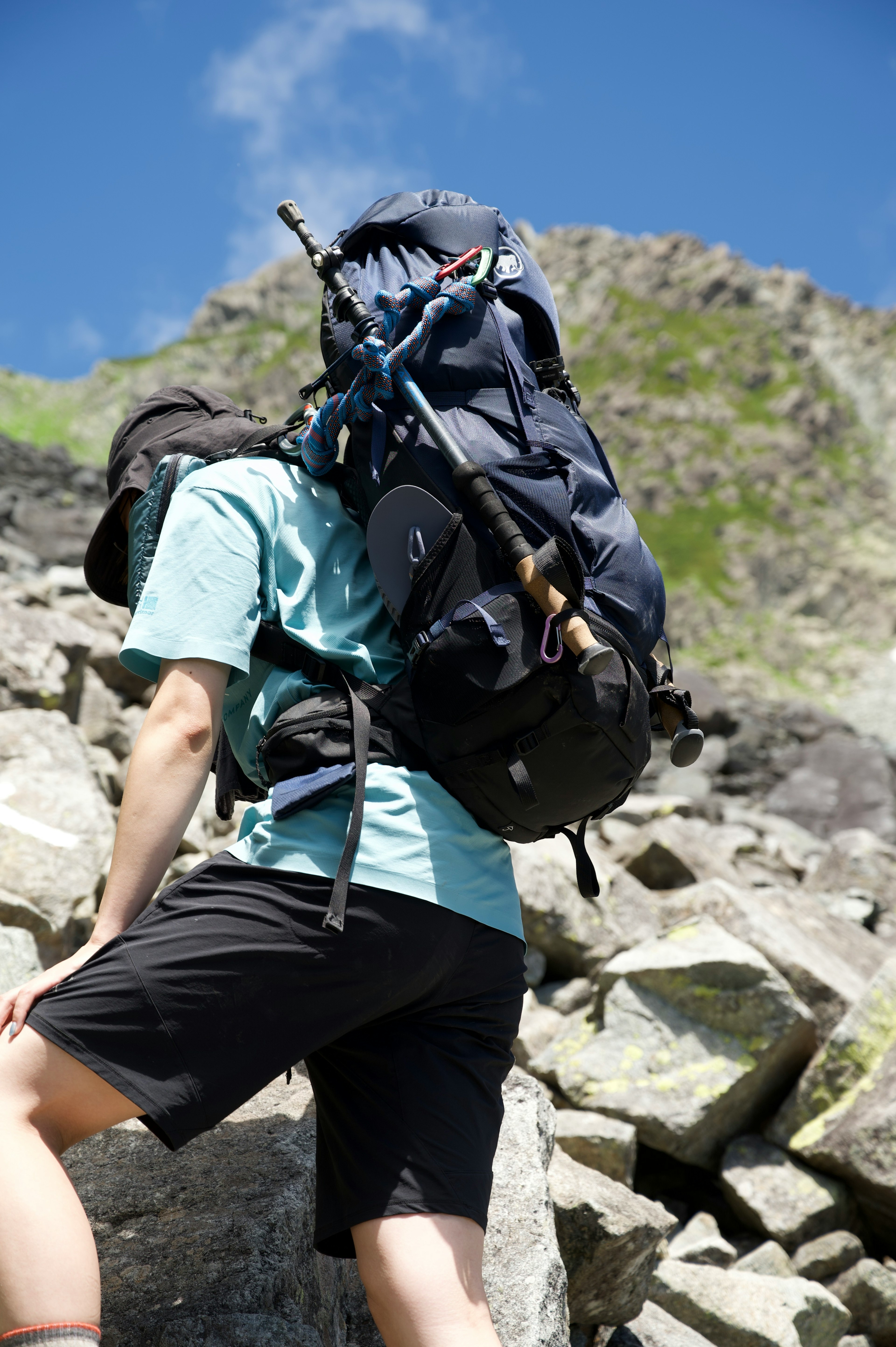 登山中の人物が大きなリュックサックを背負っている岩場を登っている様子