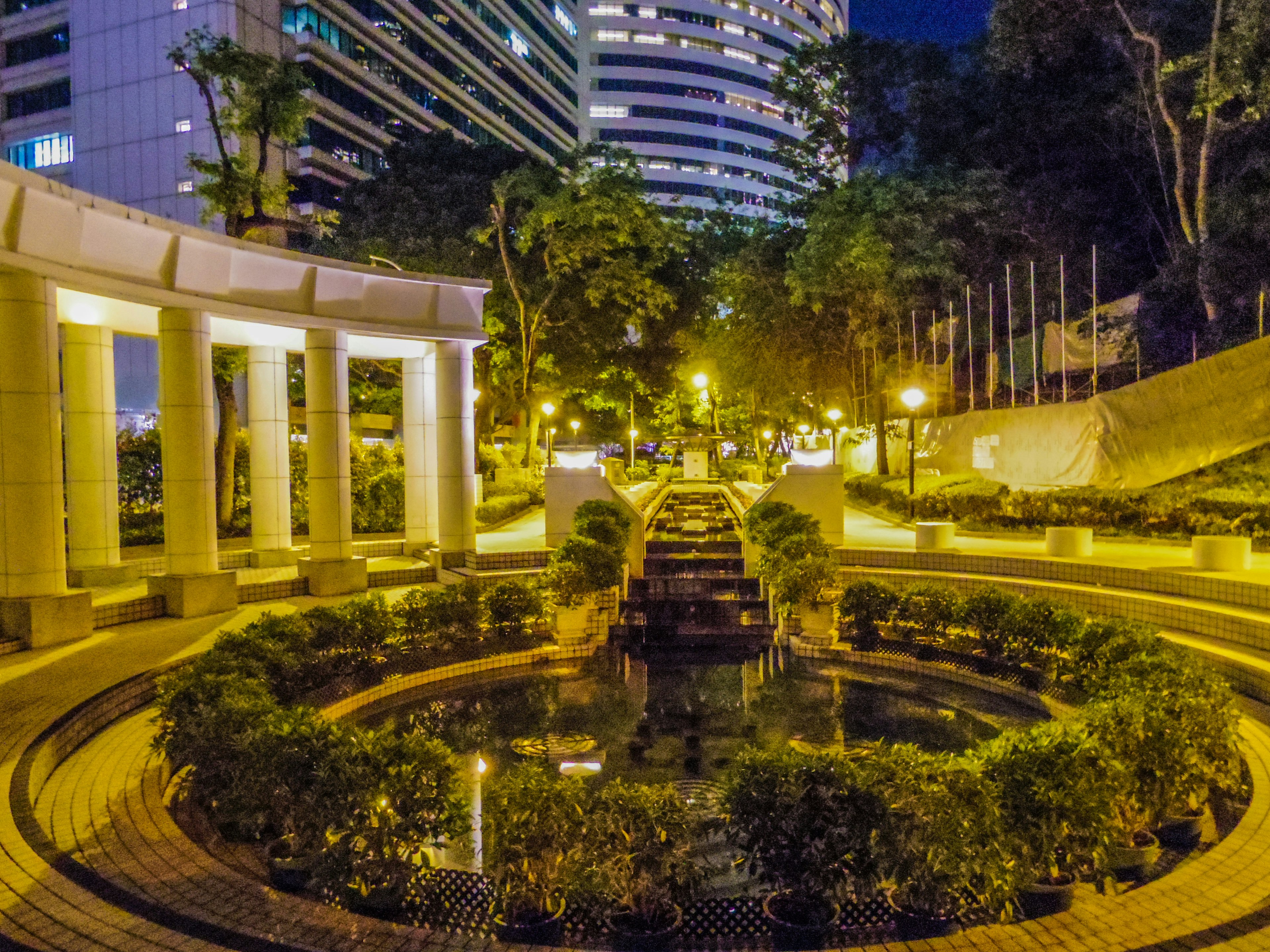 Vista notturna di un parco con fontana e verde lussureggiante