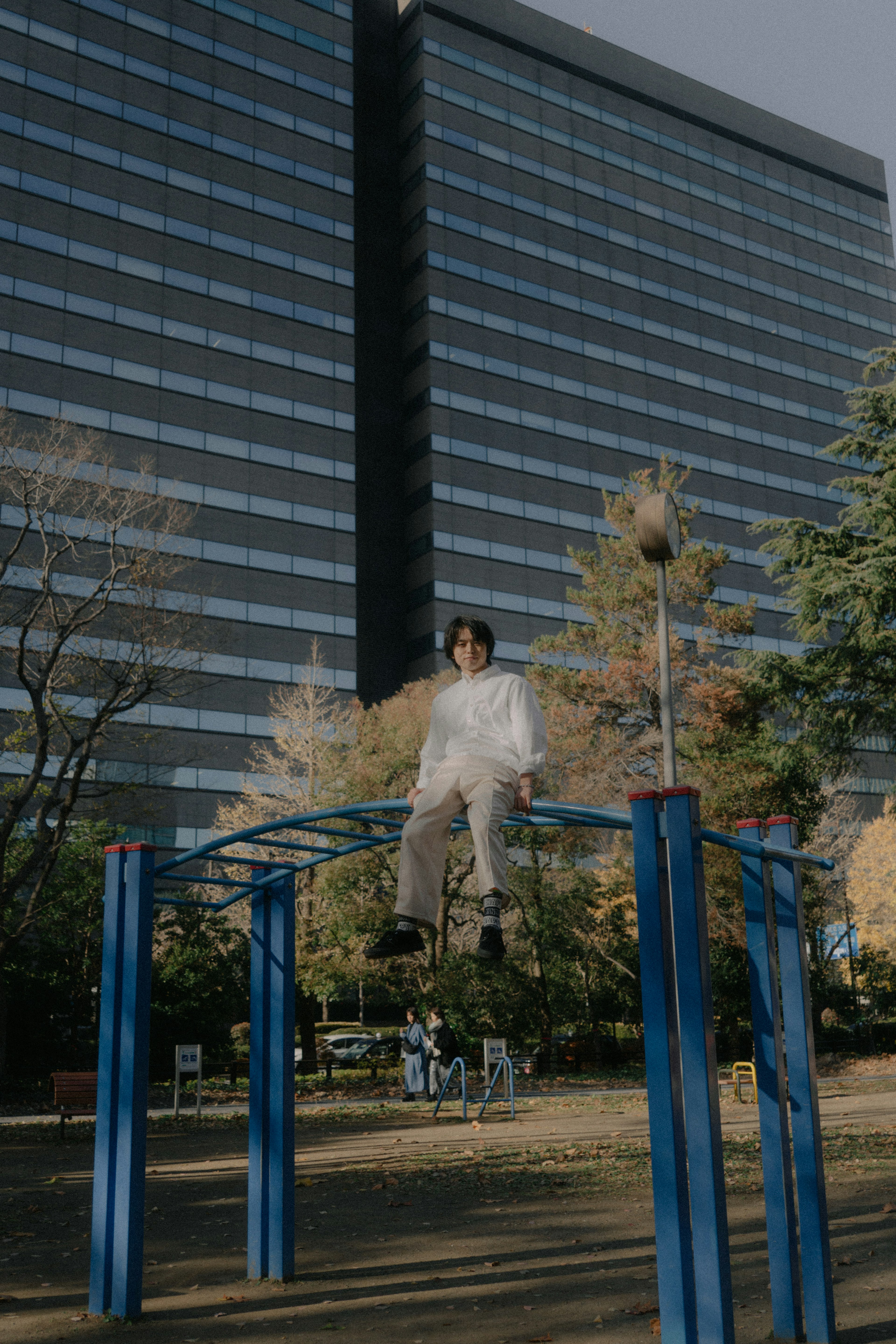 公園裡坐在藍色單槓上的人和背景中的高樓