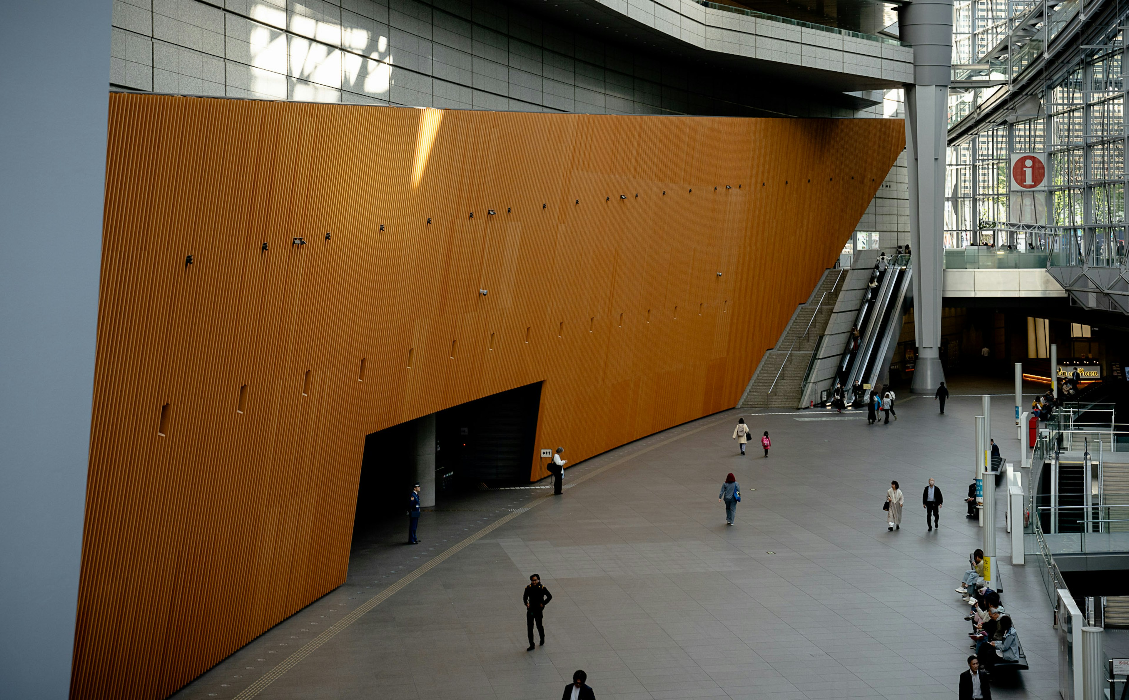 Interior de un edificio moderno con una pared naranja y personas caminando