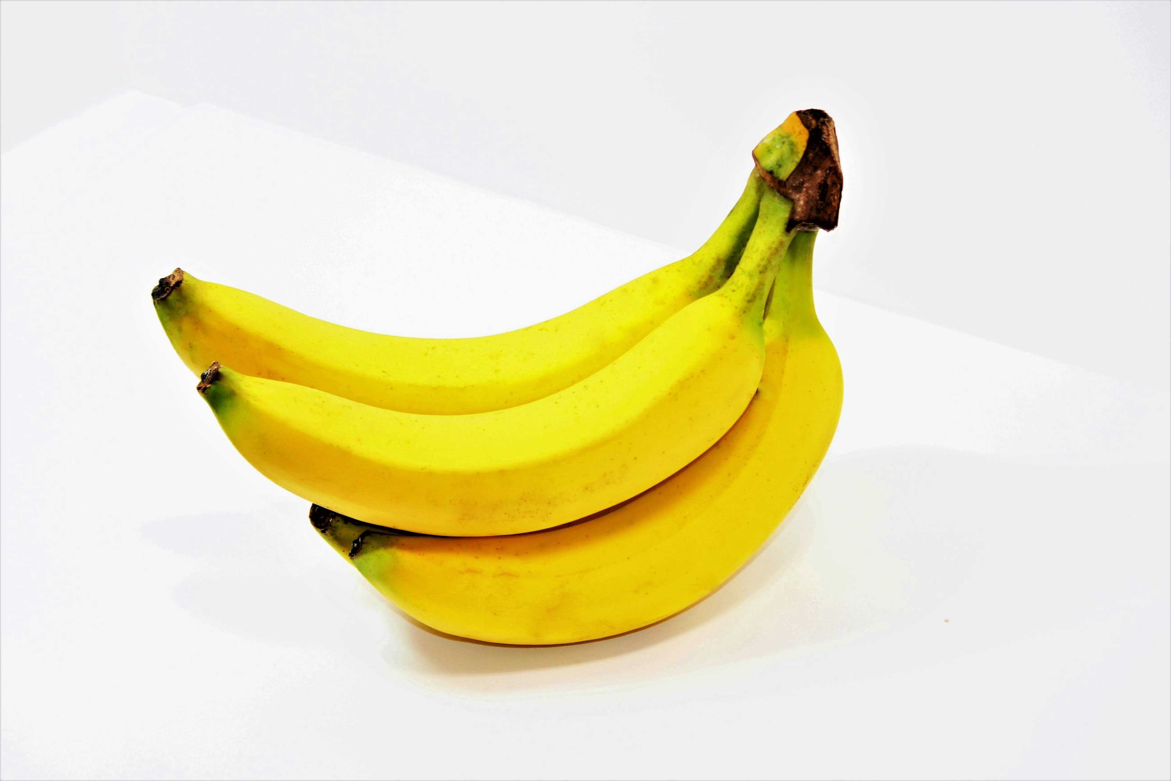 Trois bananes jaunes posées sur un fond blanc