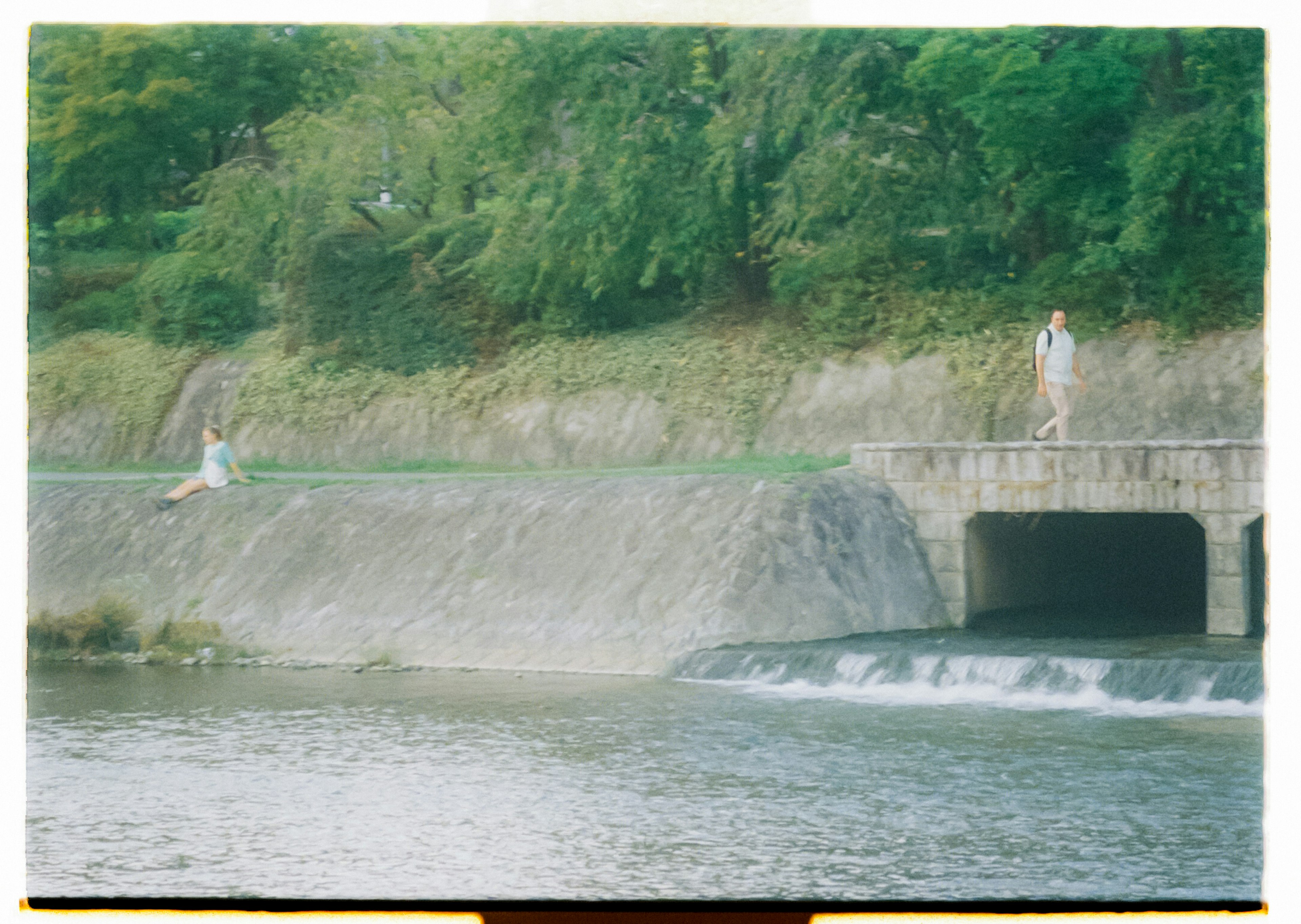 Eine ruhige Flusslandschaft mit üppigem Grün und zwei Figuren