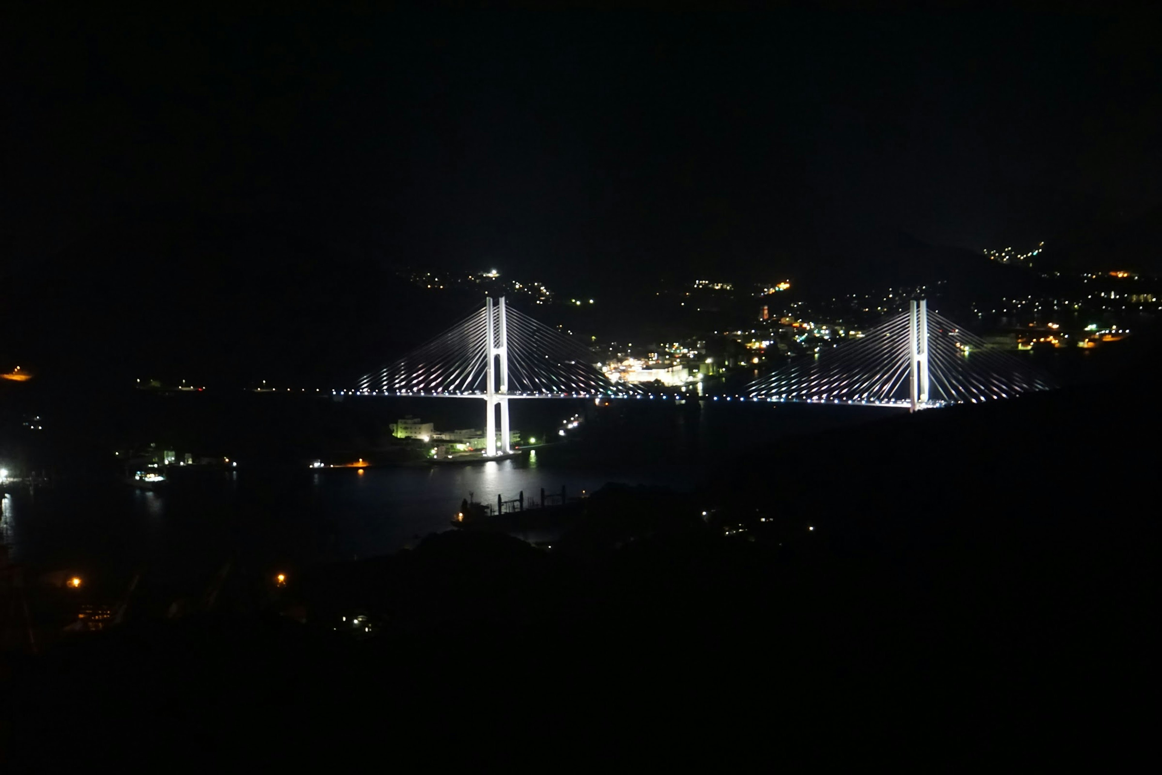 Puente iluminado de noche con luces de la ciudad circundante