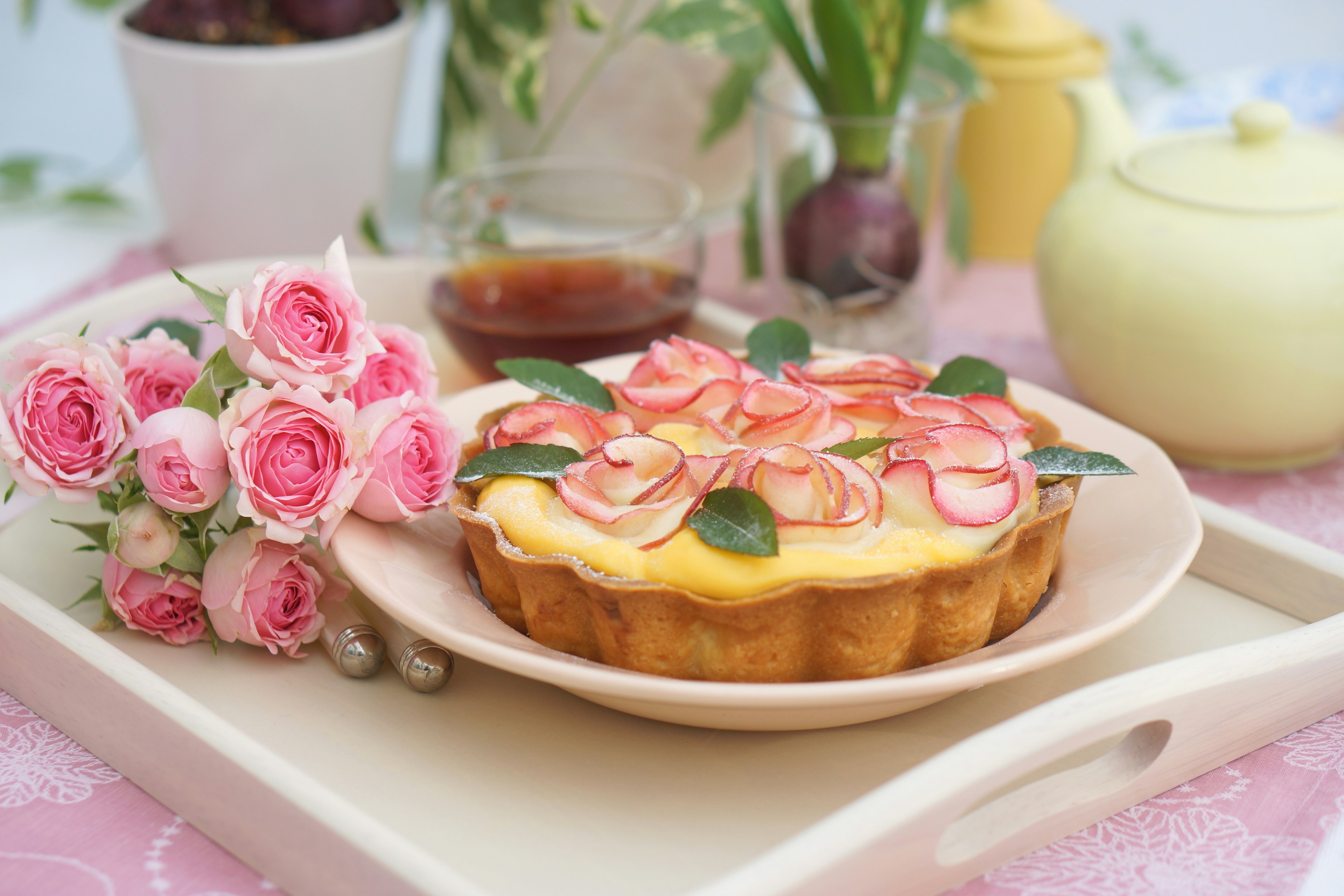 Một chiếc bánh tart được trang trí đẹp mắt với hoa hồng trên đĩa trắng đặt trên bàn