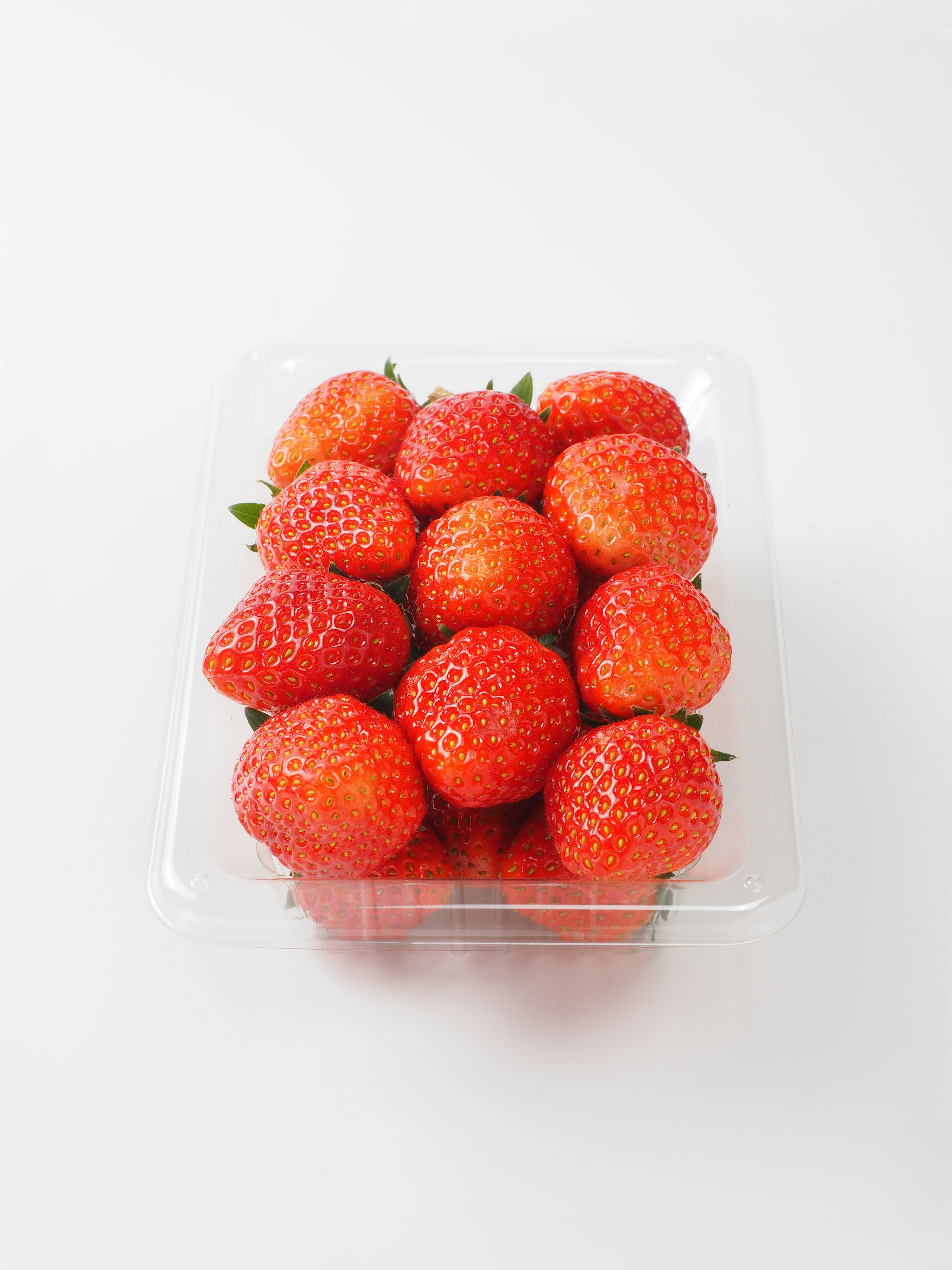 A clear container filled with fresh strawberries