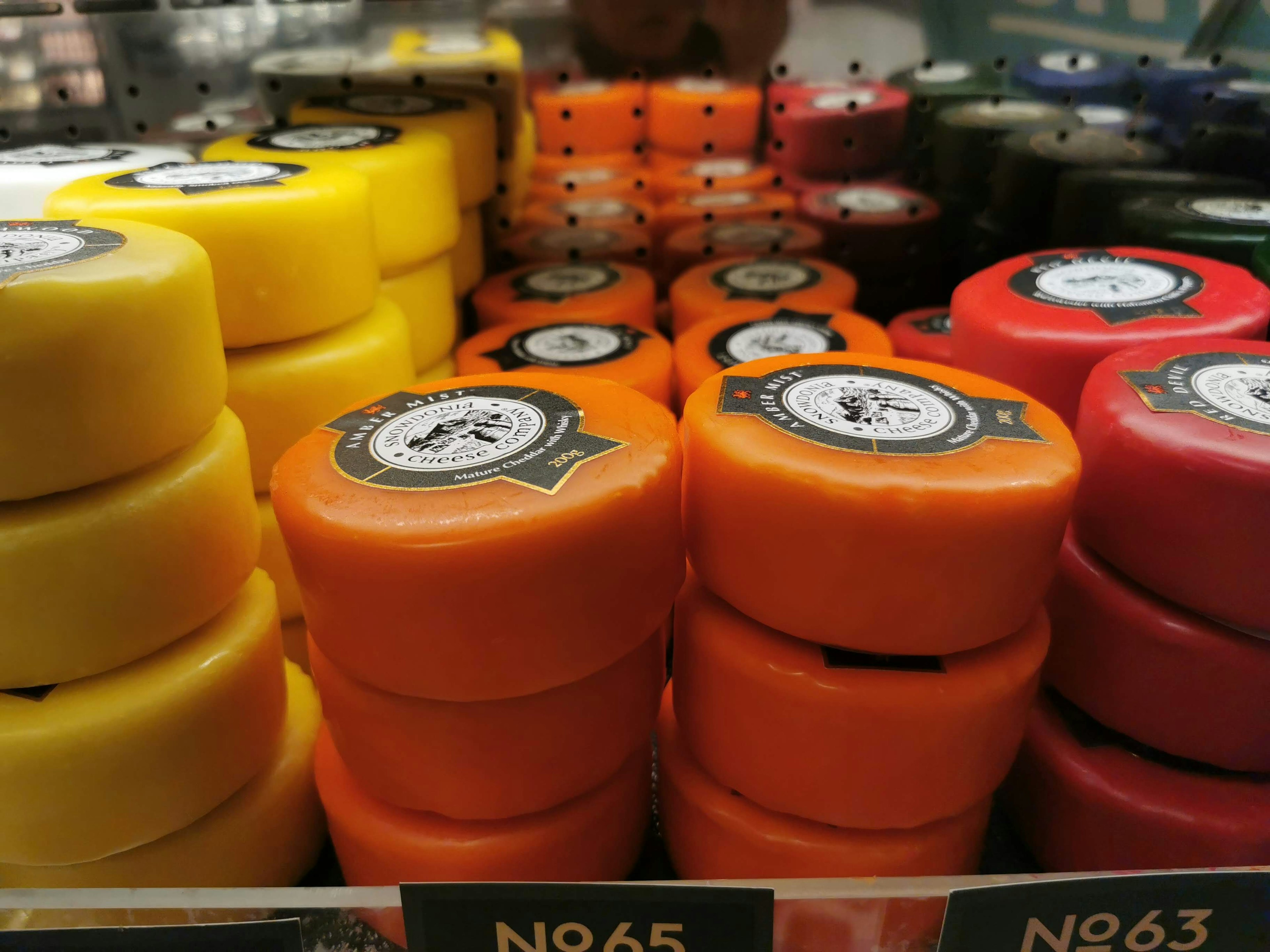 Colorful cheese wheels stacked on a supermarket shelf