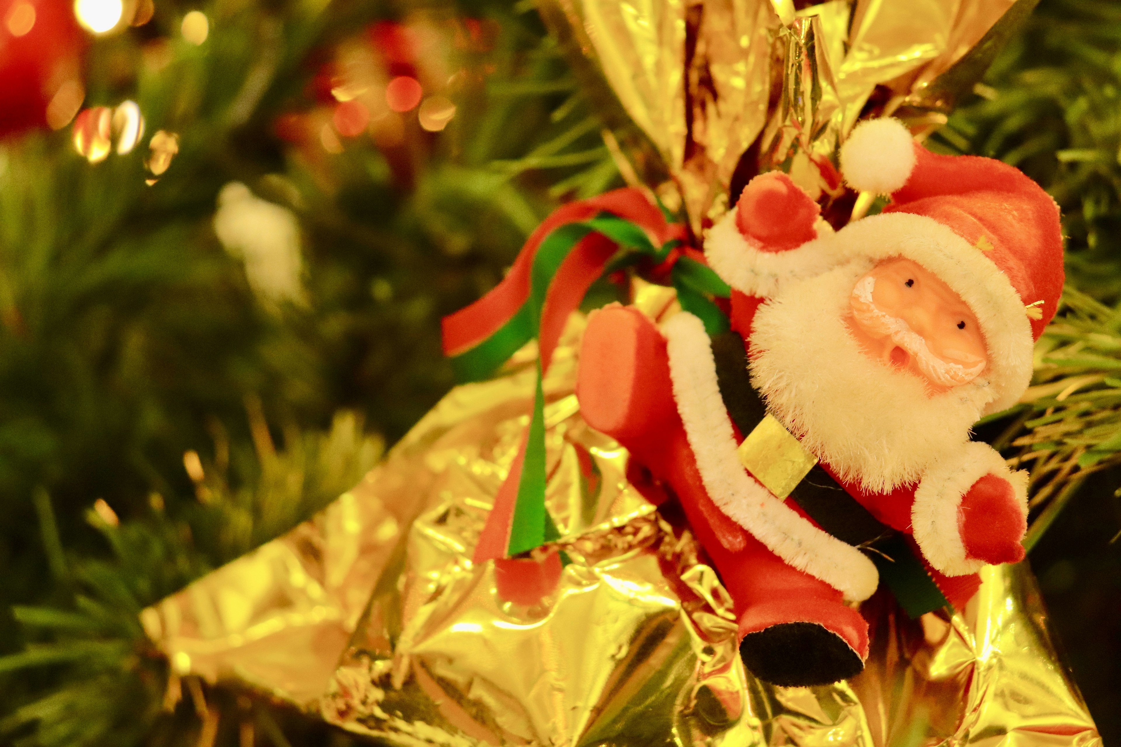 Santa Claus ornament on a Christmas tree with golden wrapping