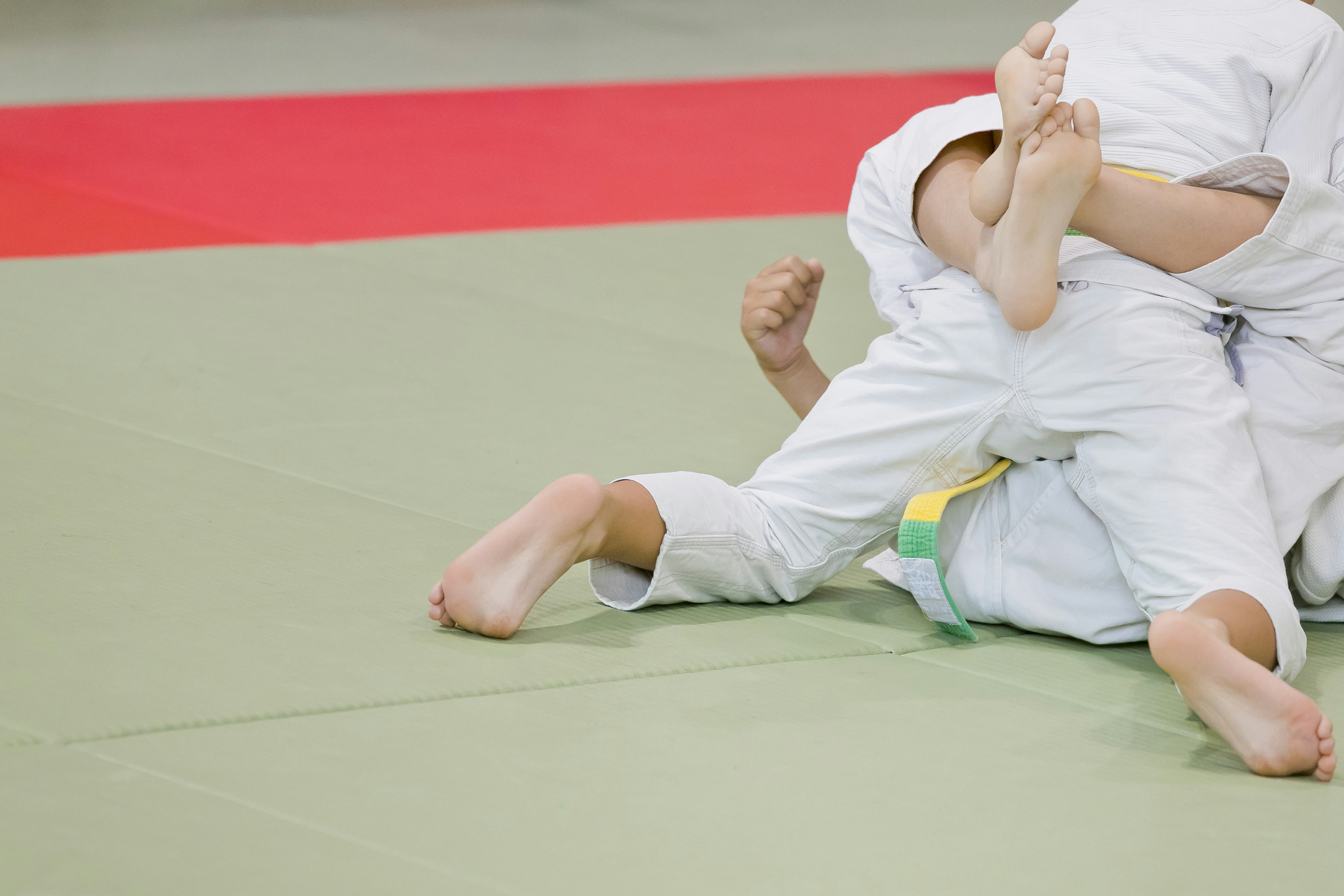 Kedua pemain judo dalam pertandingan menunjukkan kaki dan bagian tubuh