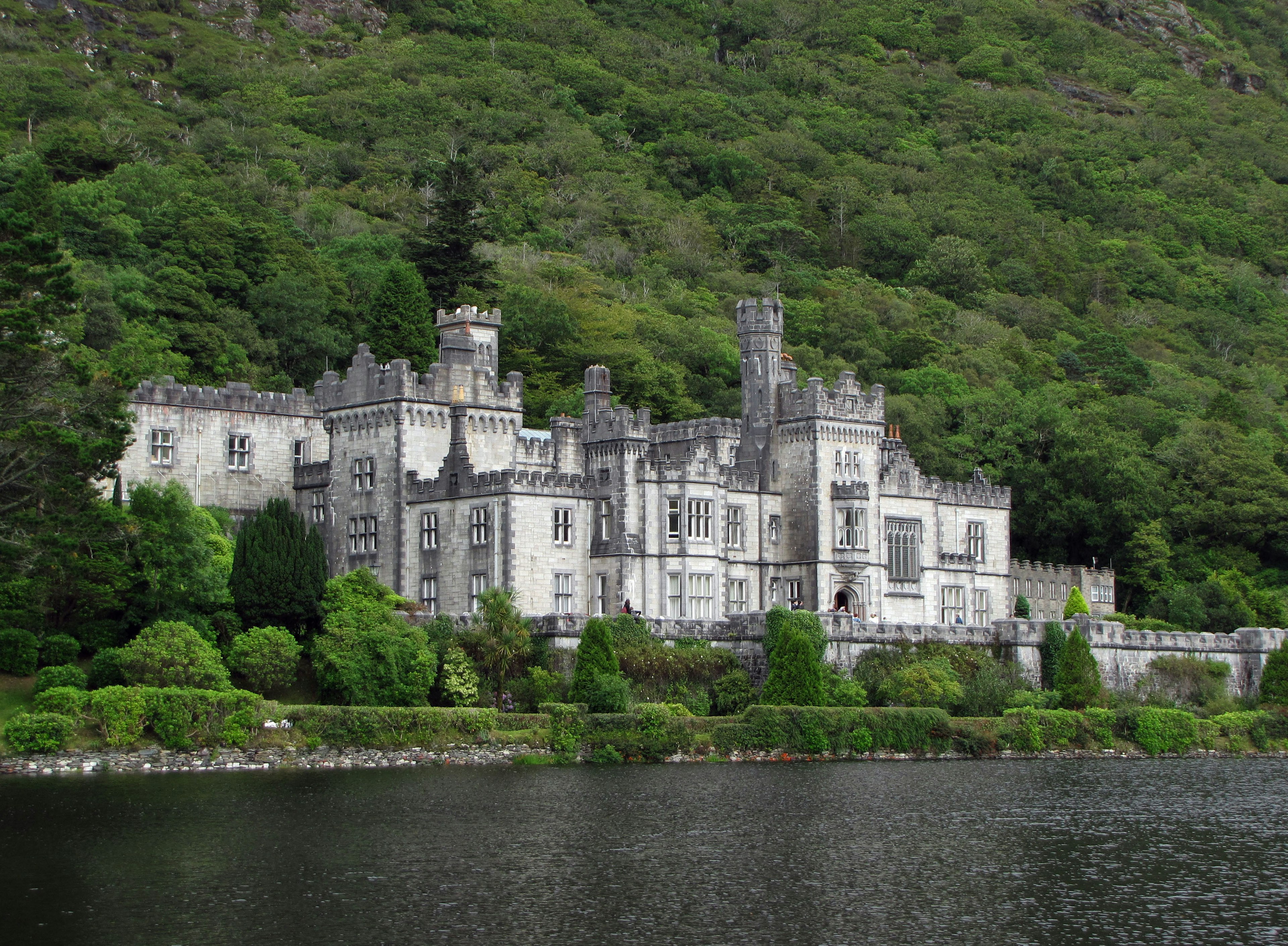 Beau château près d'un lac entouré de montagnes verdoyantes