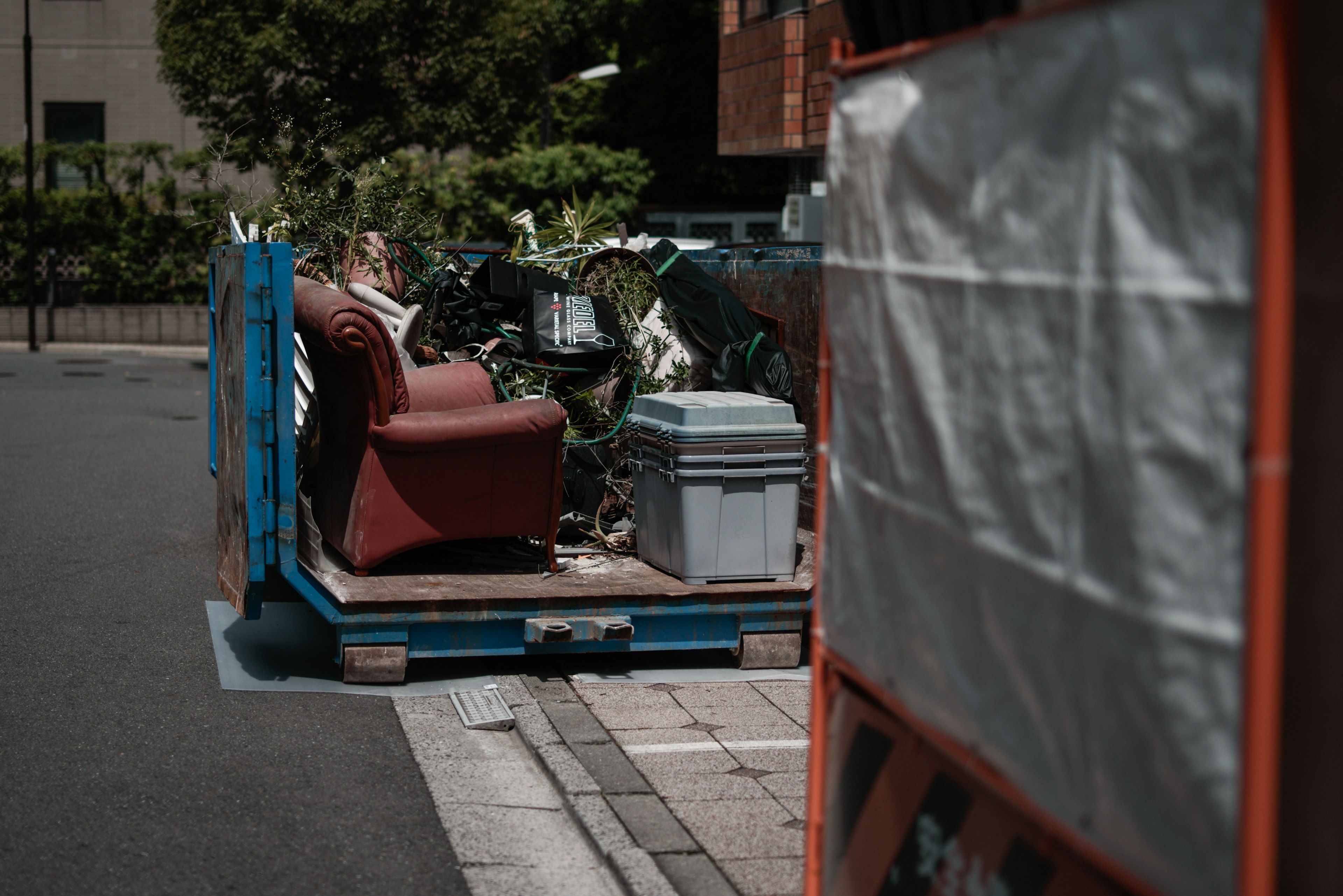 赤いソファとゴミが置かれた通りの風景