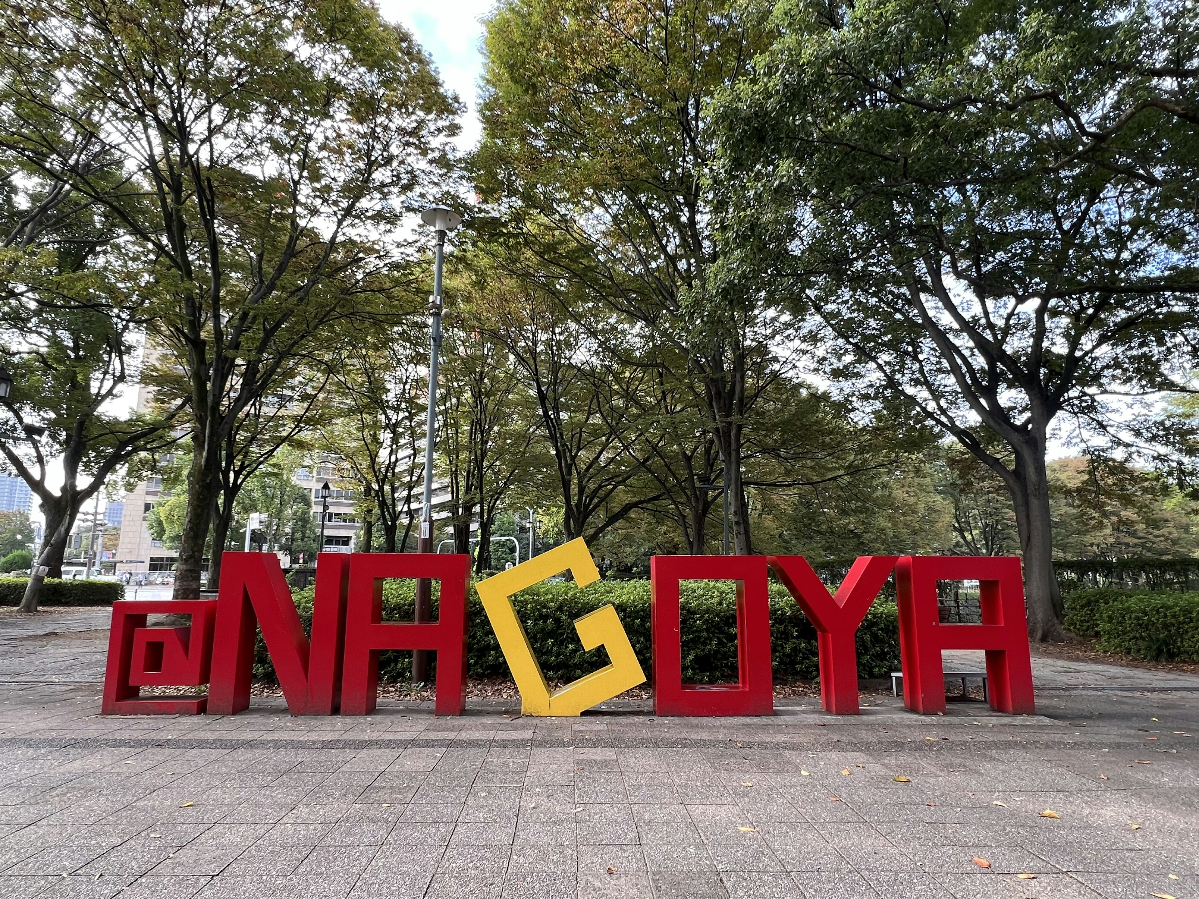 Insegna colorata con '@NAGOYA' circondata da alberi