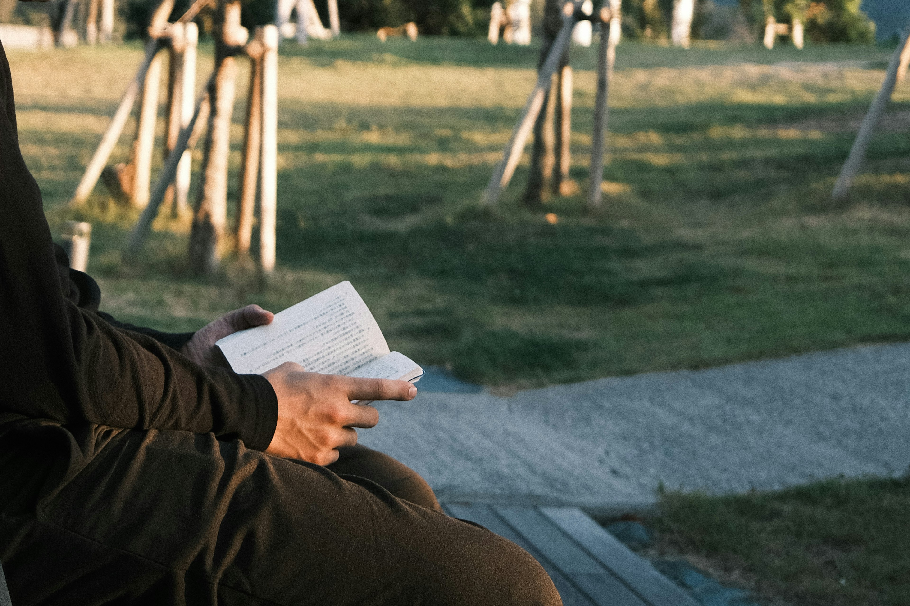 Person holding a book in a park setting