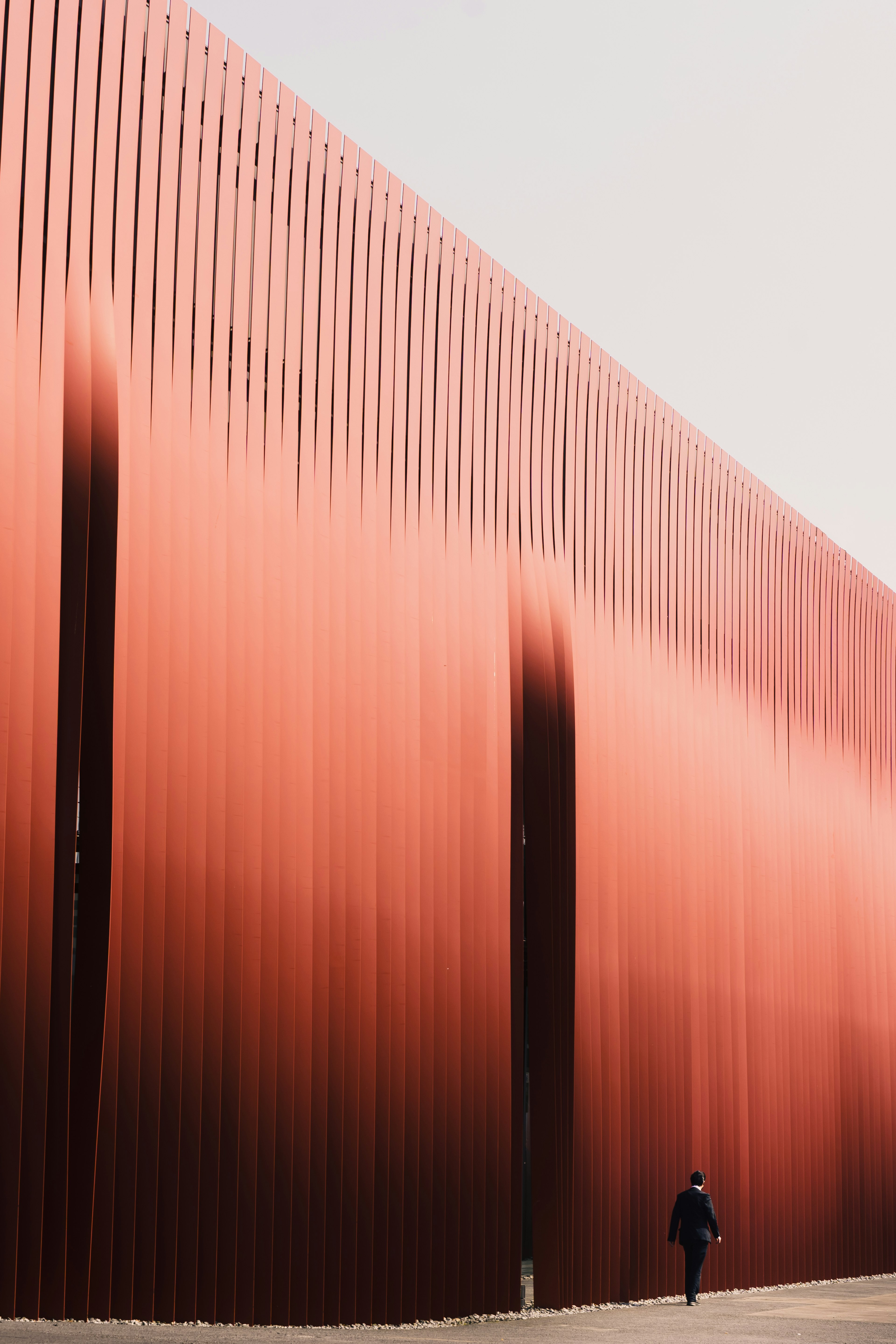 A person walking in front of a red metal wall