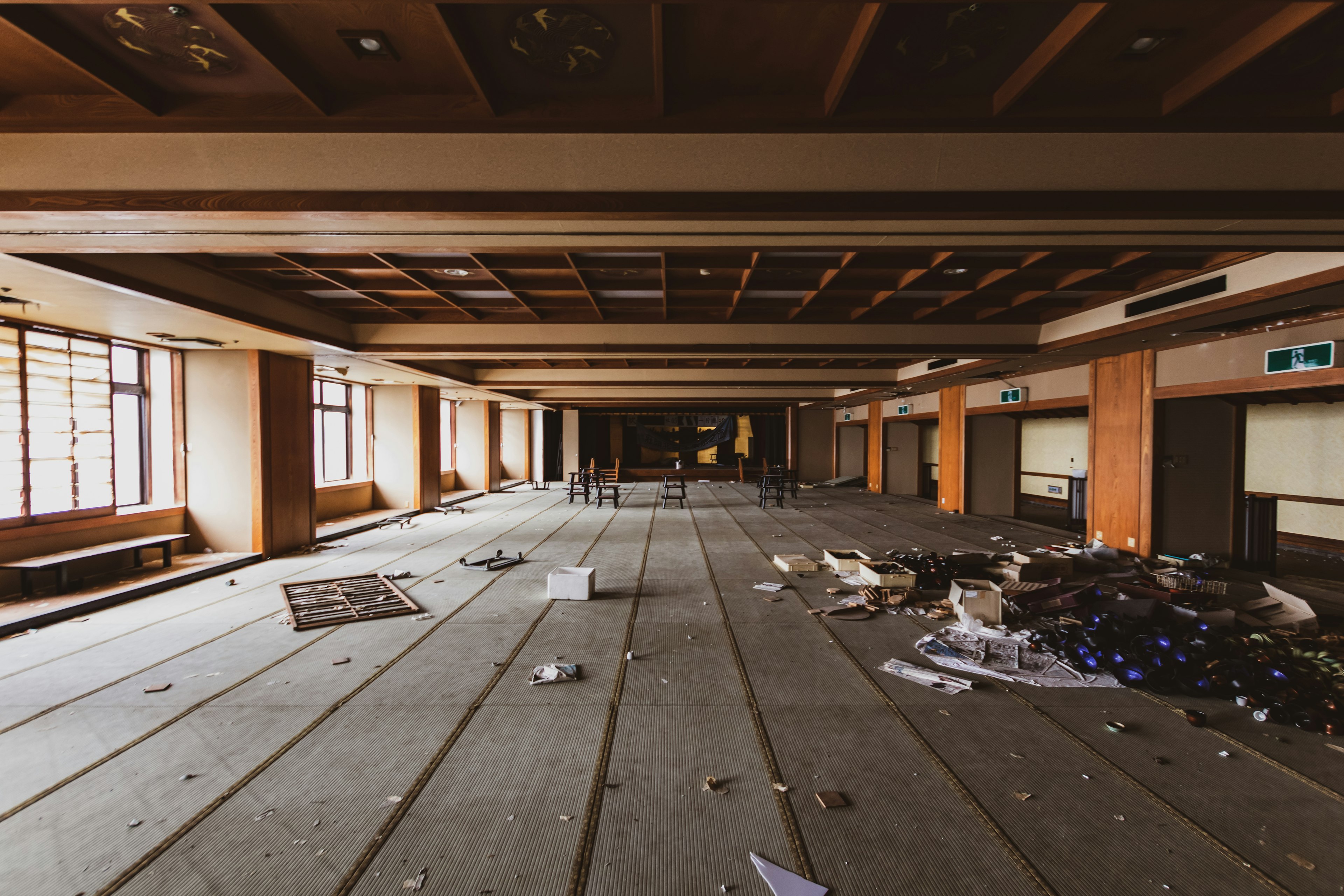 Spacious empty room with scattered debris and old wooden ceiling