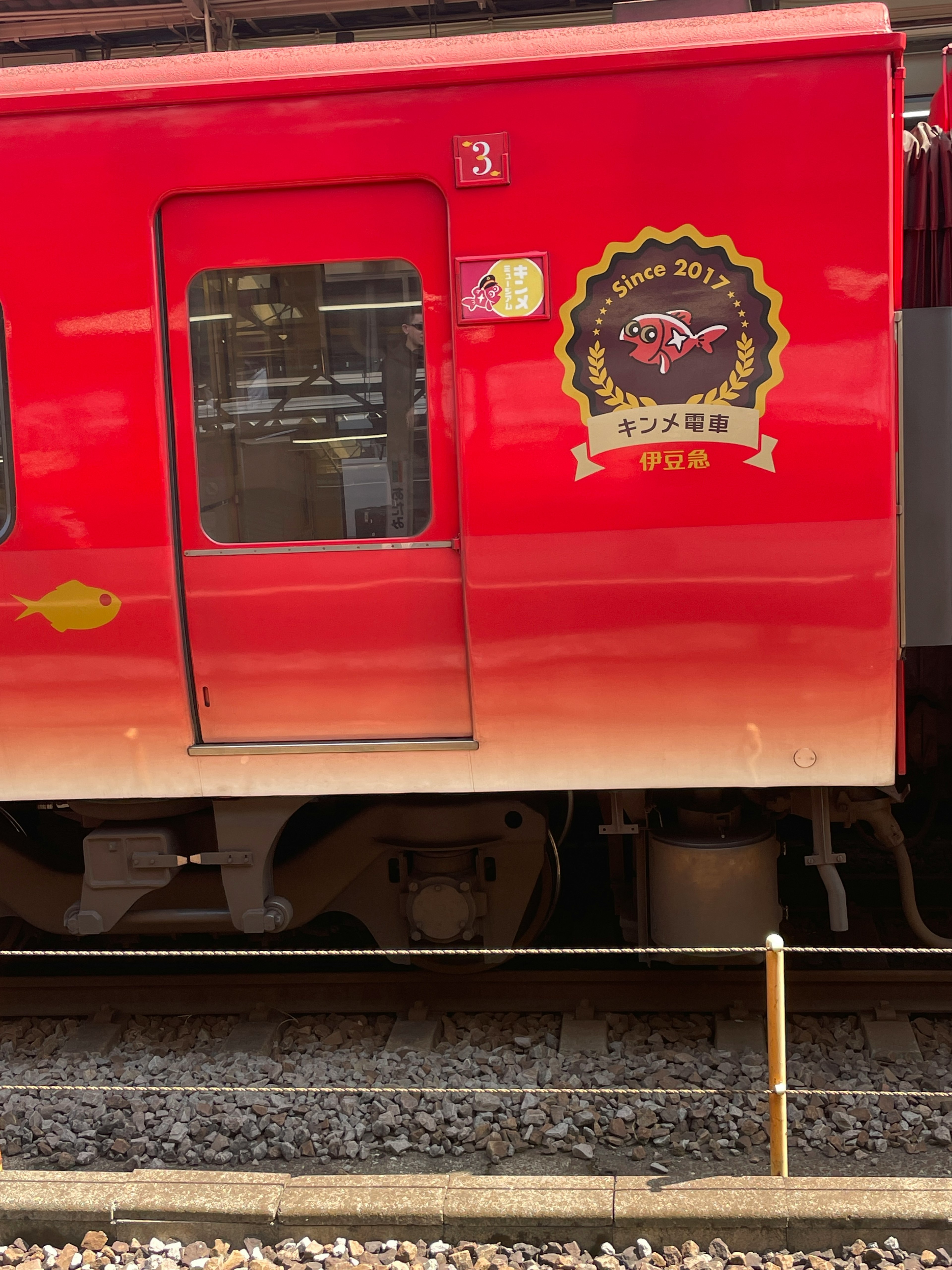 Vista lateral de un tren rojo con un logo y una ventana