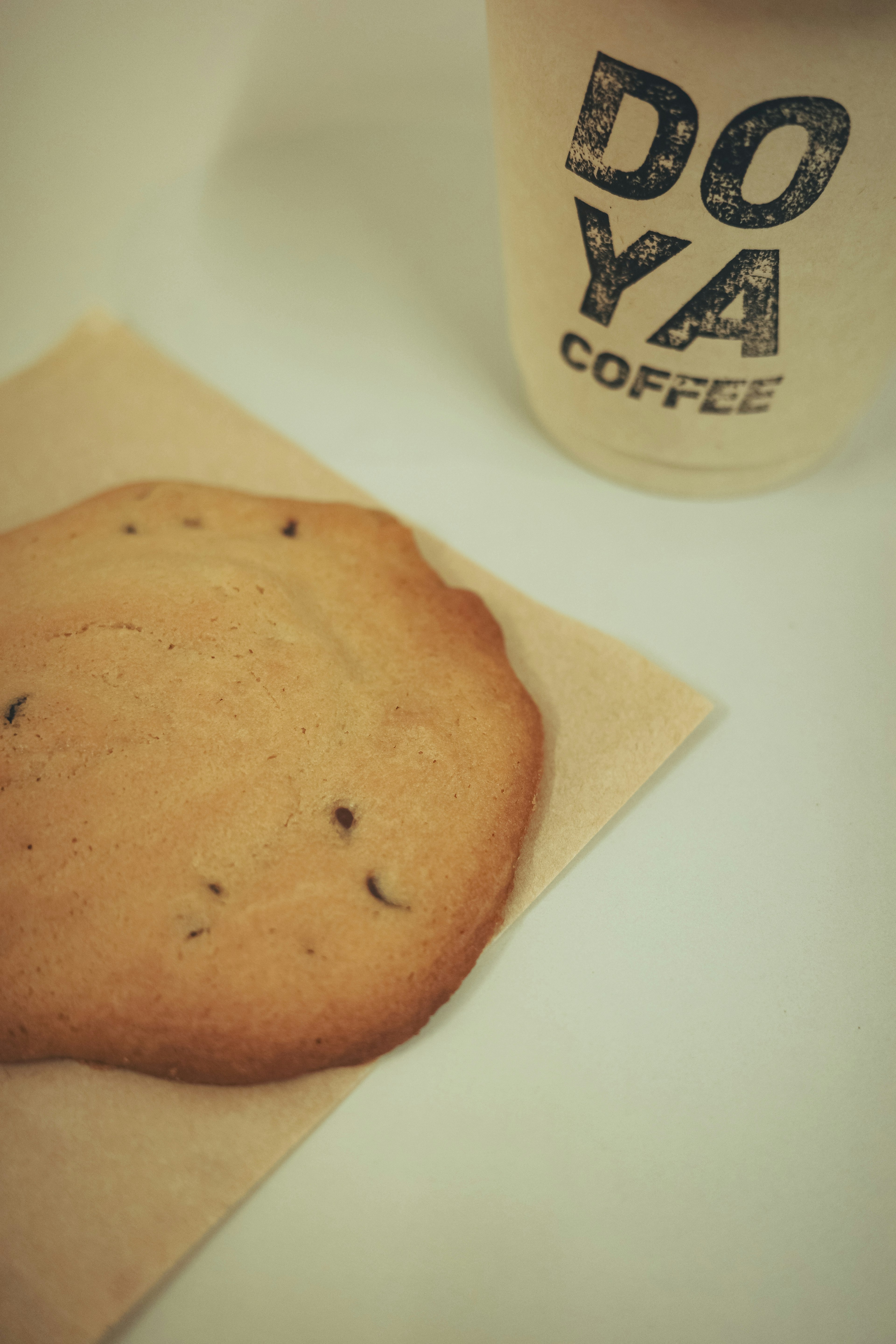 Una galleta colocada sobre una servilleta junto a una taza de café