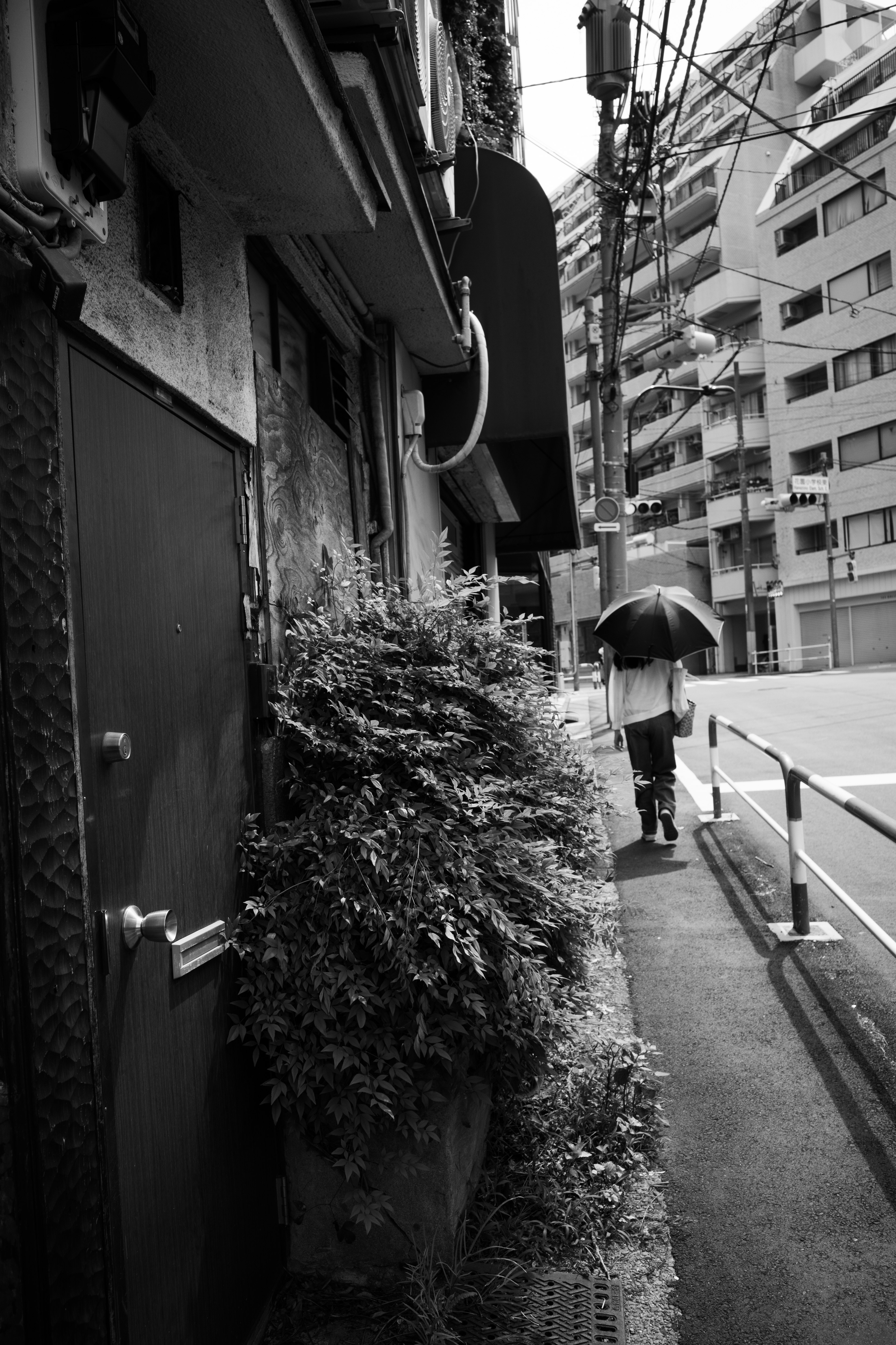 Una persona caminando con un paraguas en un paisaje urbano en blanco y negro