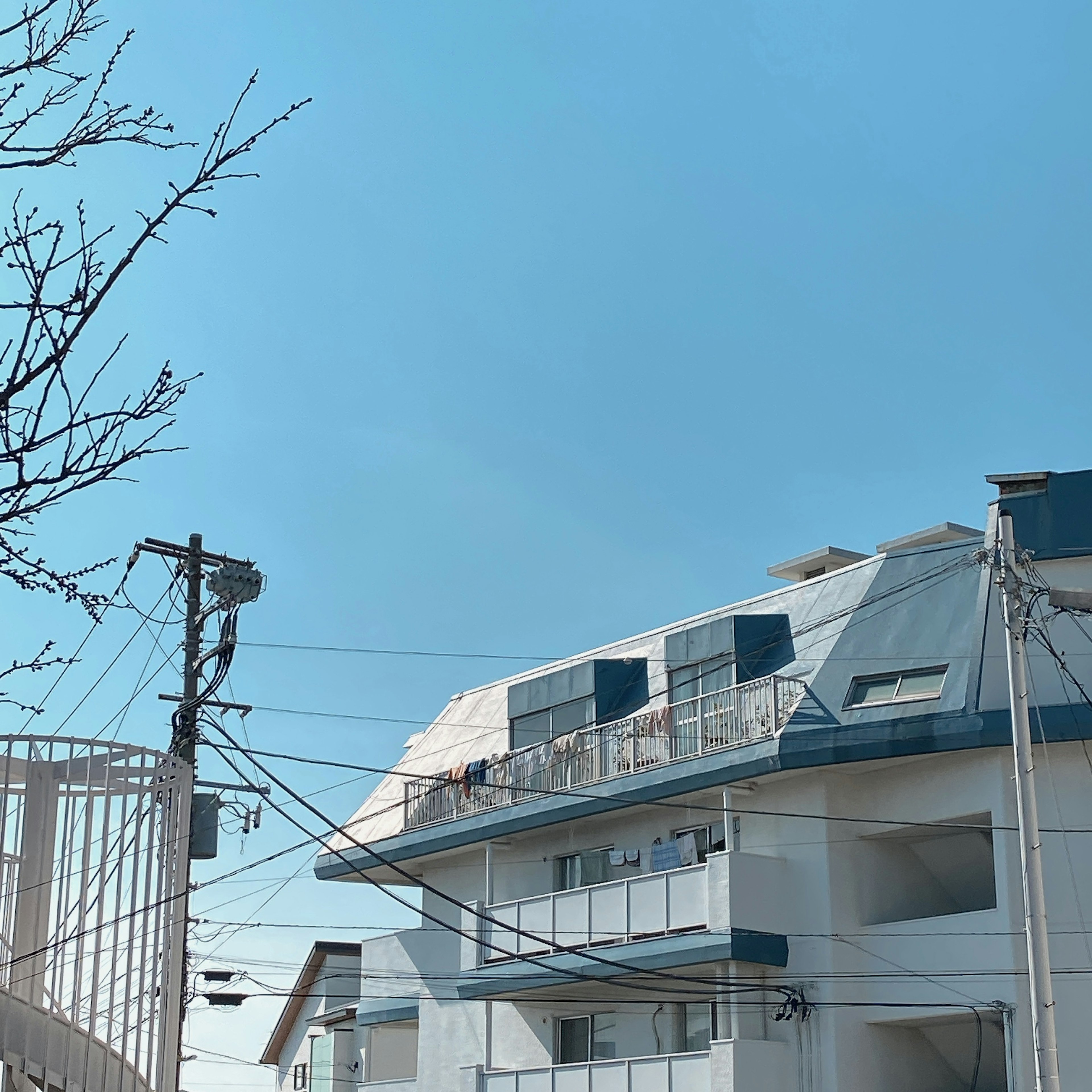 A white apartment building under a blue sky with visible power lines