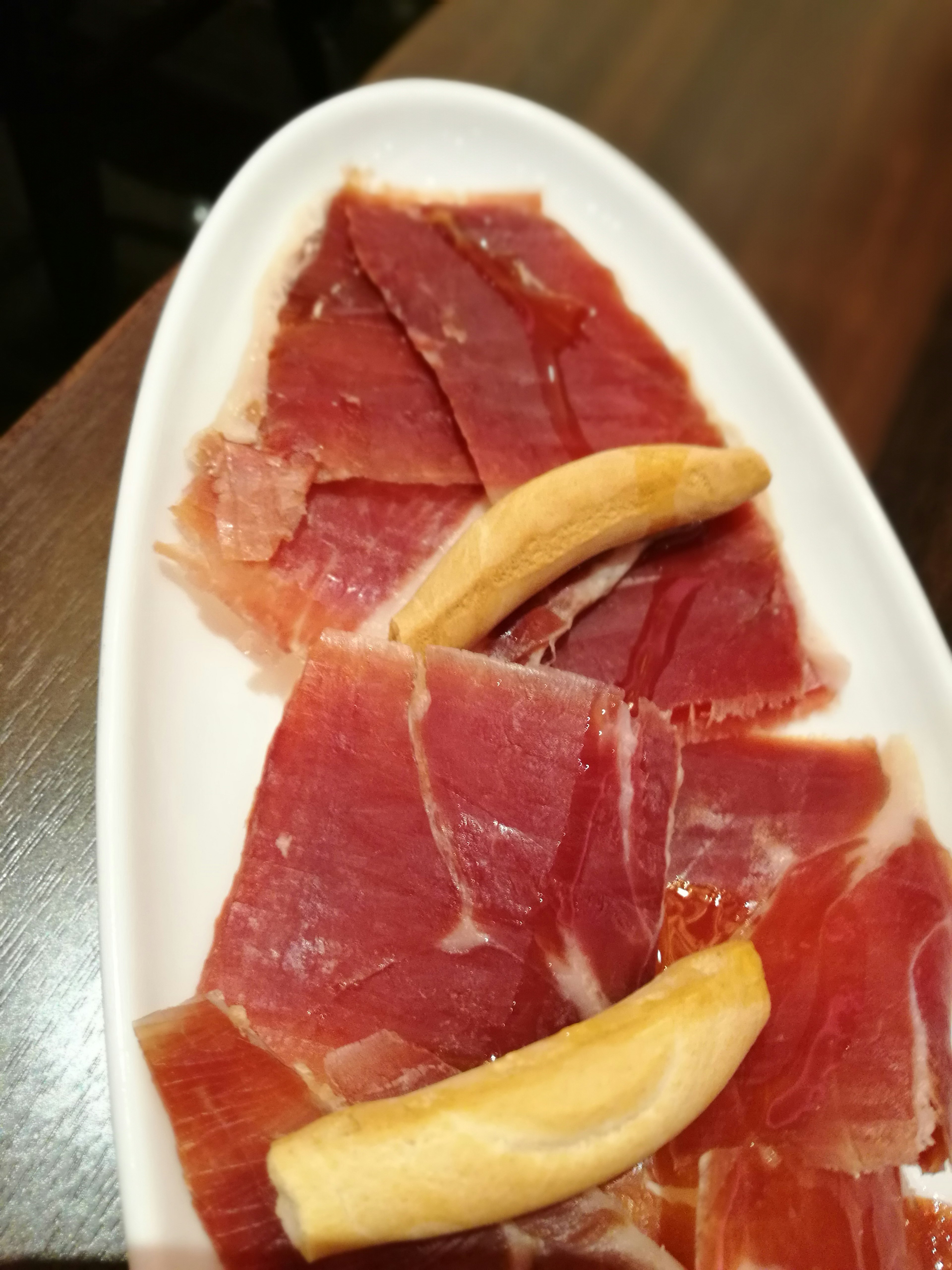 Slices of Jamón Serrano and banana on a white plate