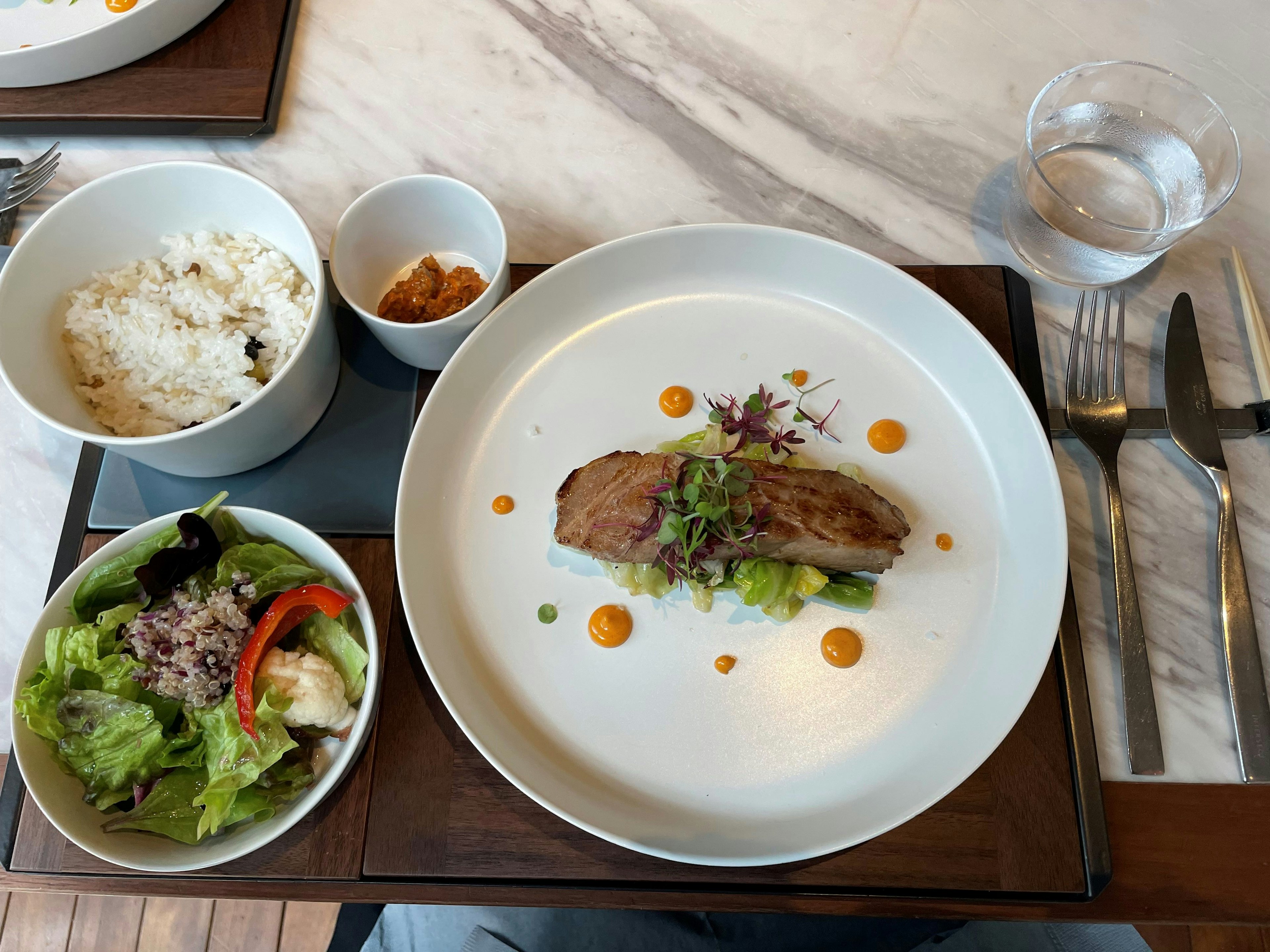 Hidangan utama yang disajikan dengan indah bersama salad nasi dan makanan penutup dalam suasana makan yang elegan