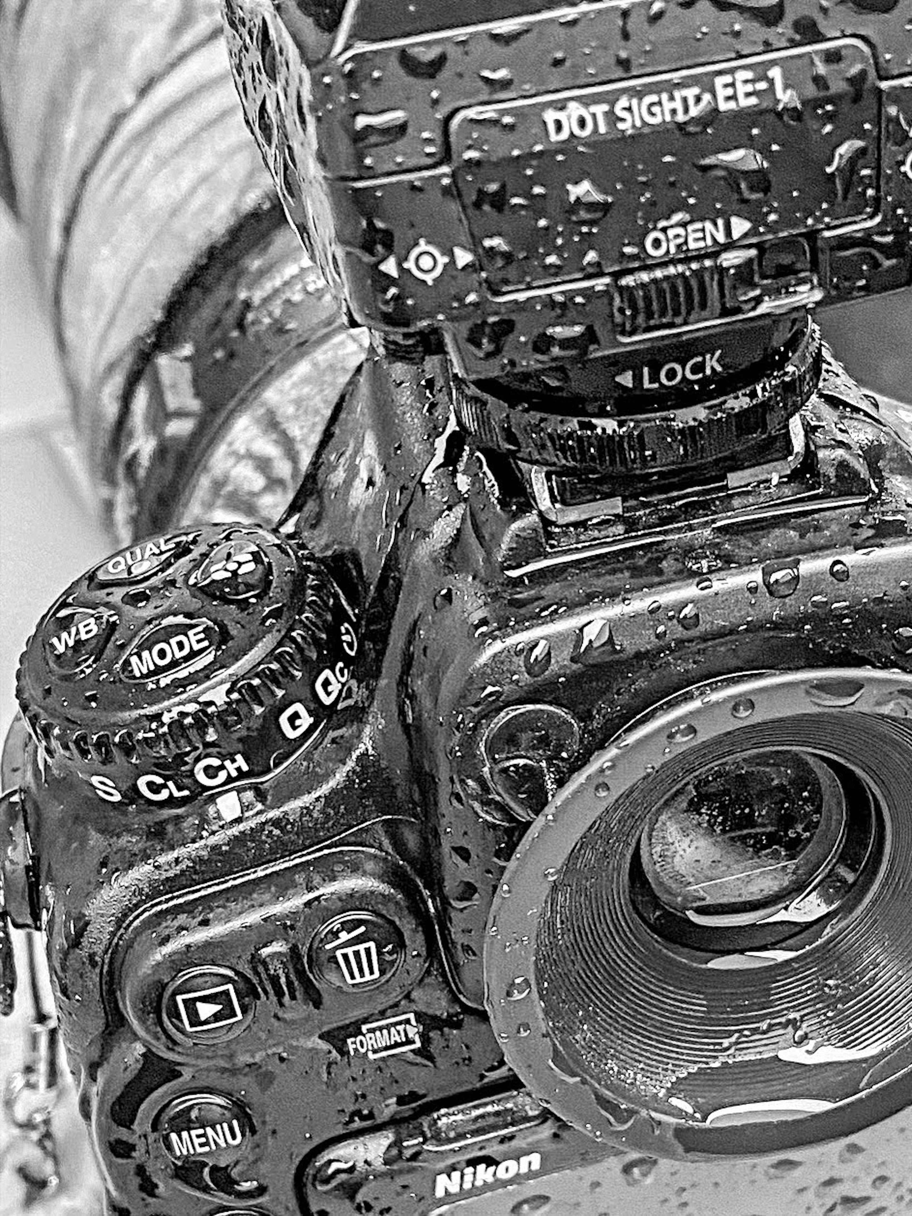 Close-up of a wet Nikon camera showcasing various buttons and lens details