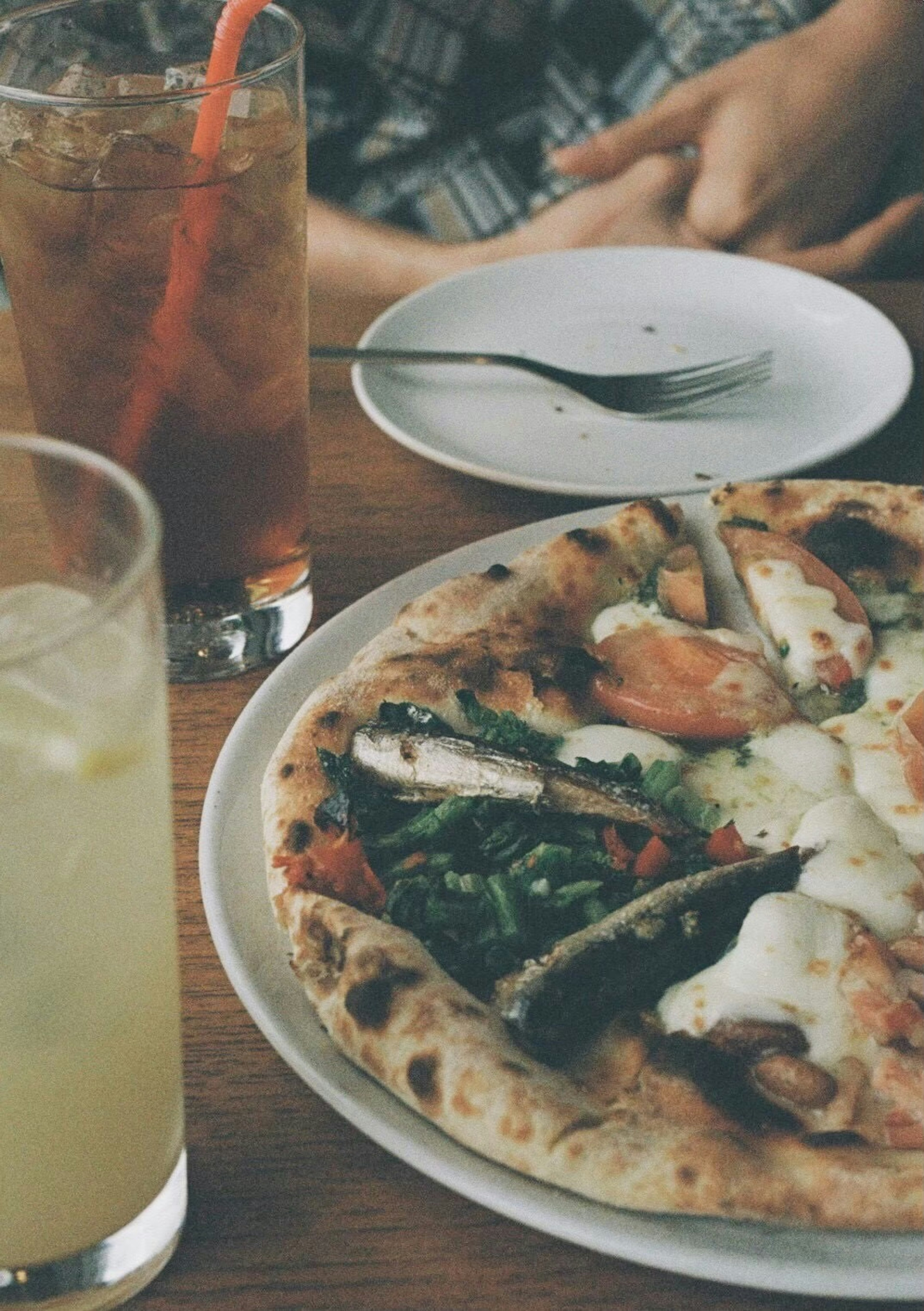 Leckere Pizza mit Belag und Getränken auf einem Holztisch