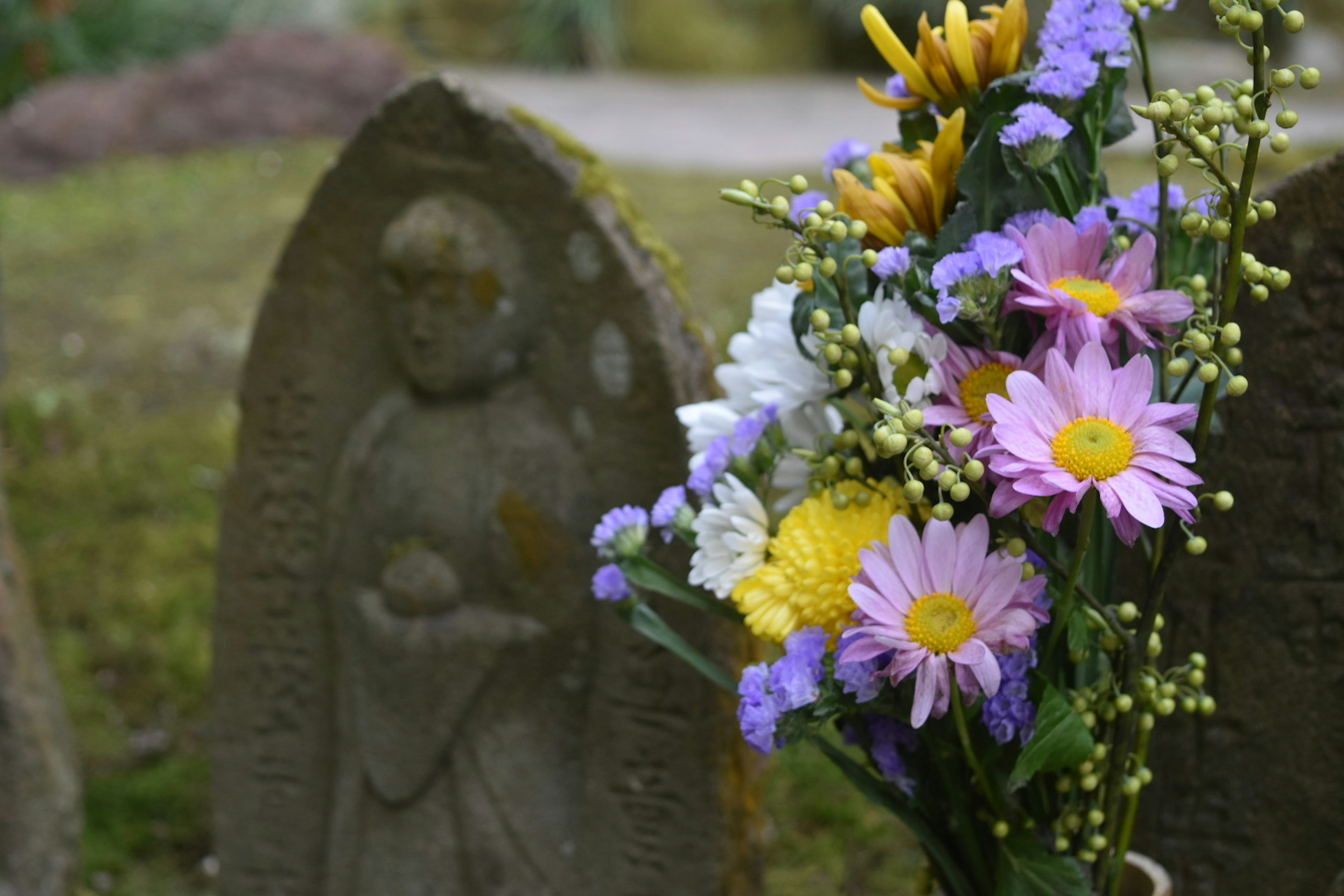 Un bouquet de fleurs colorées devant une pierre tombale