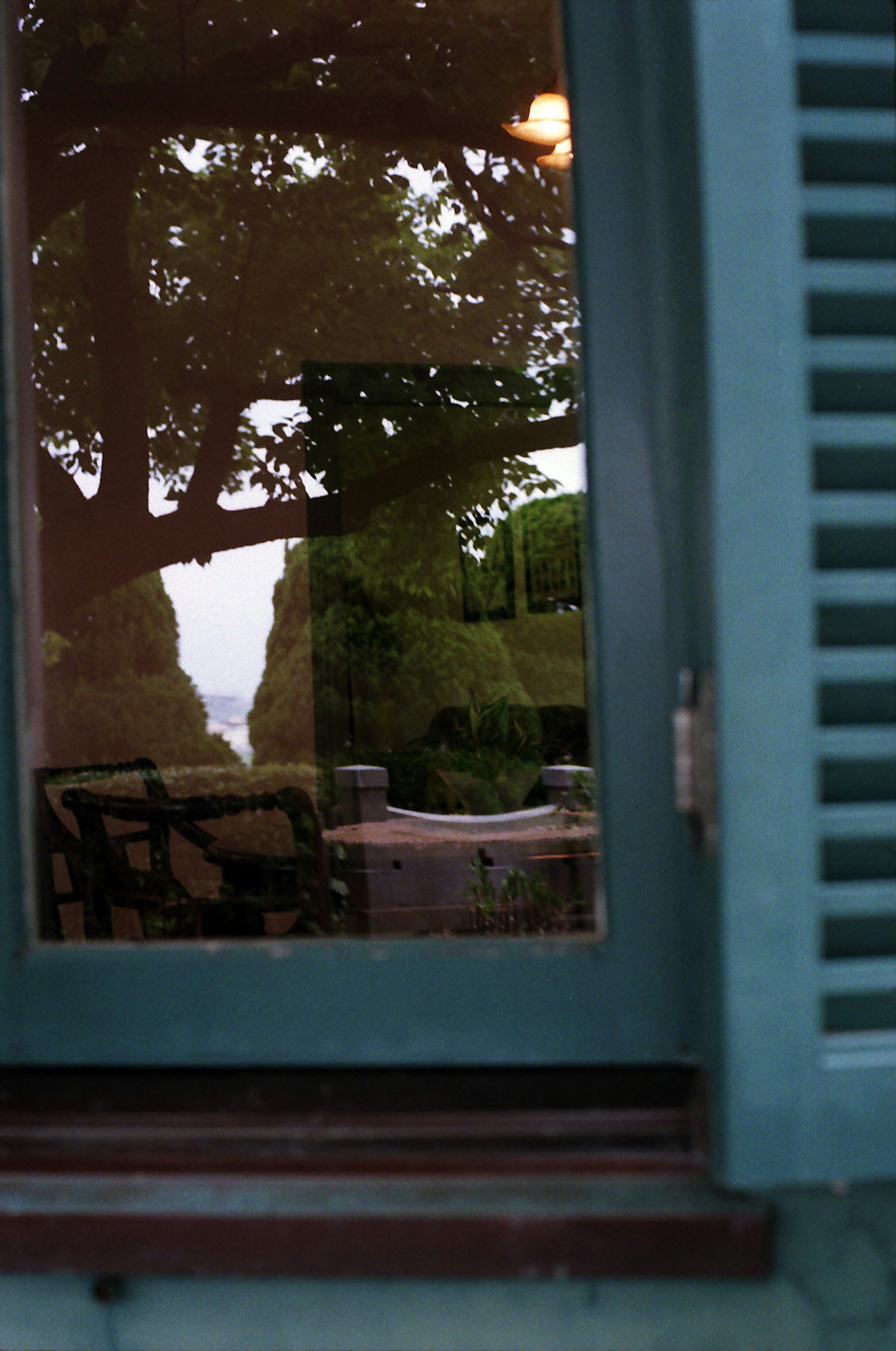 Reflet d'un jardin vert et d'une table vu à travers une fenêtre