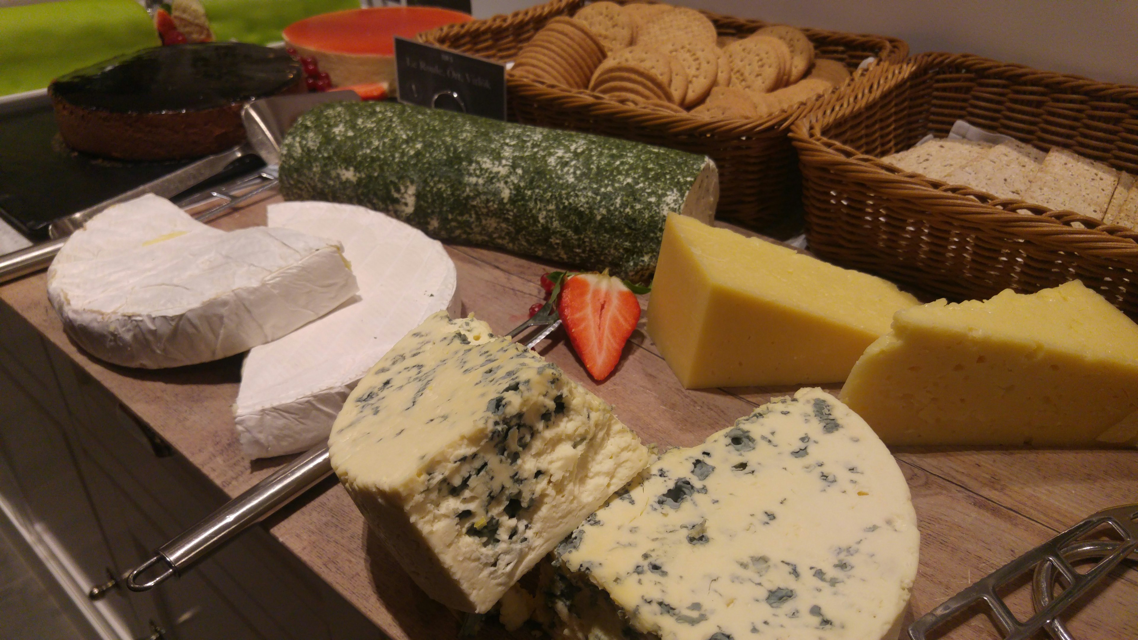 An assortment of cheeses including blue cheese and crackers on a wooden board